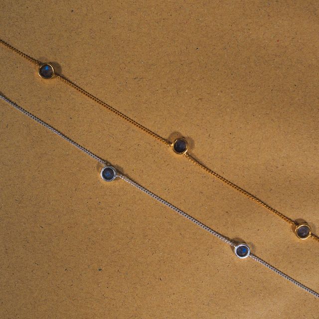 Two layered gemstone necklaces arranged on a warm-toned brown paper background