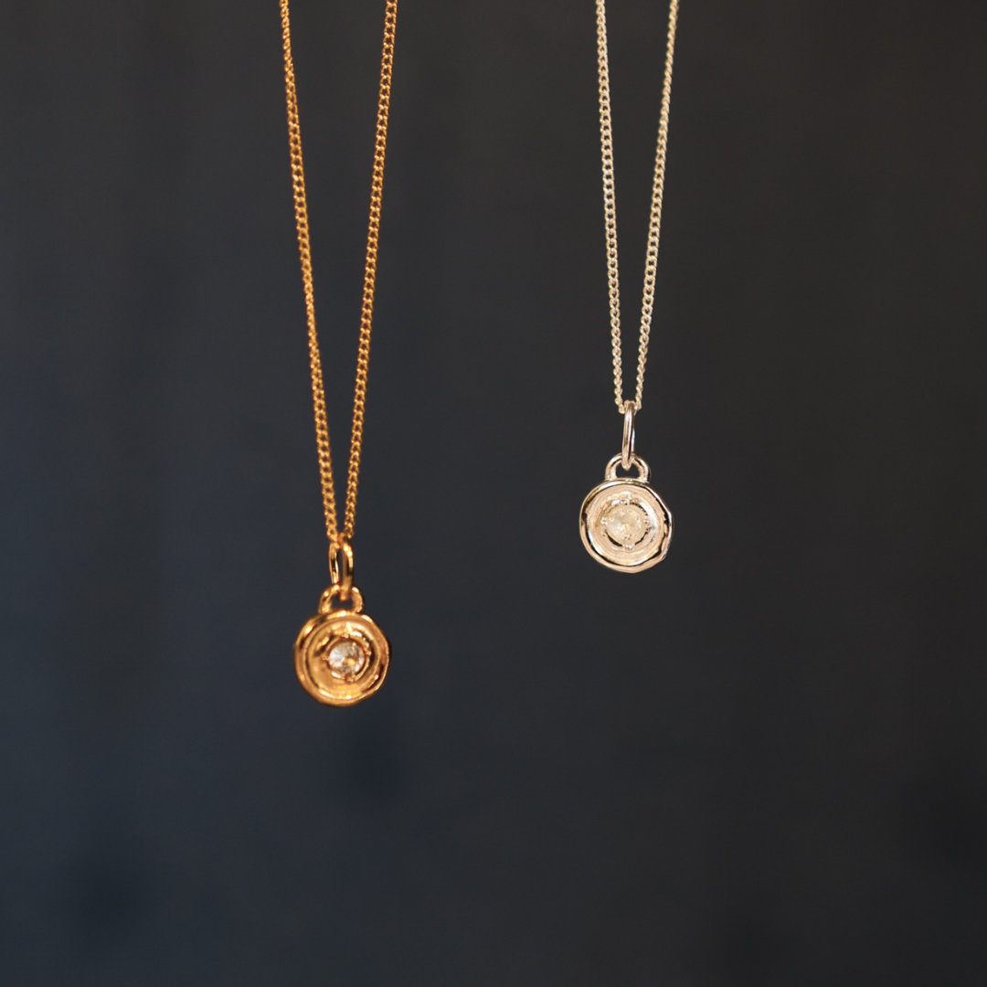 Two gold necklaces with pendants on a dark background