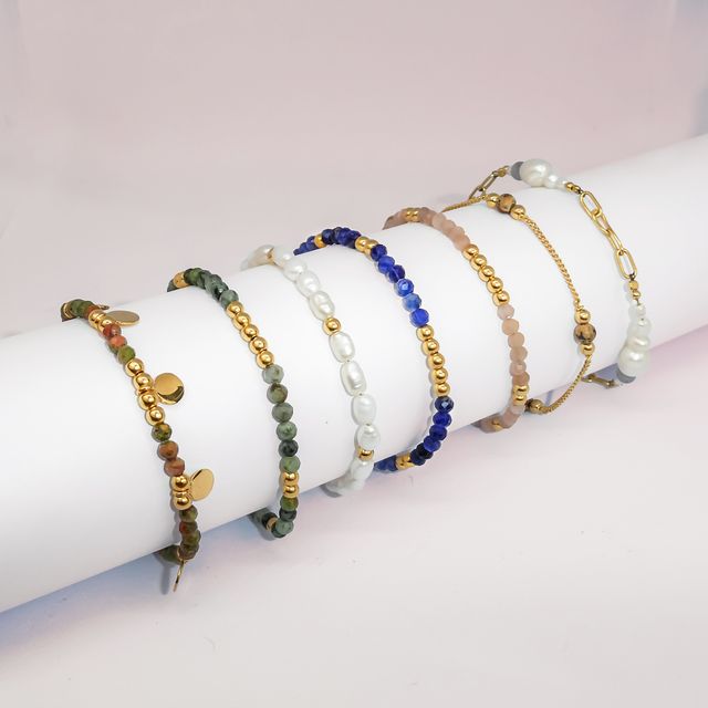 Minimalist display of a gemstone bracelet styled on a white roll stand.