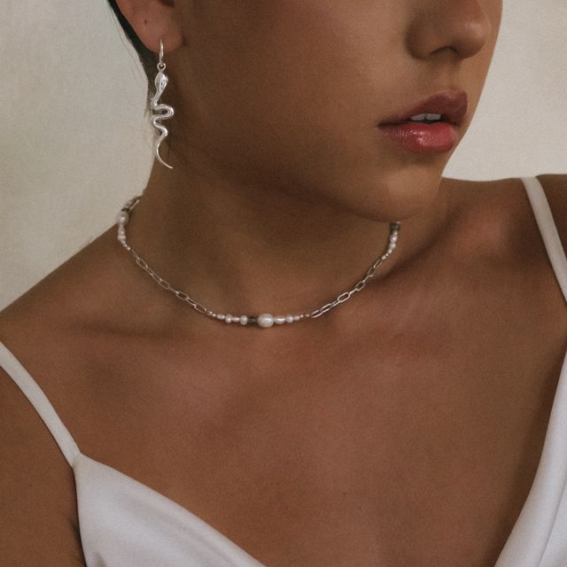 Close-up of a jewelry set featuring earrings and silver necklace