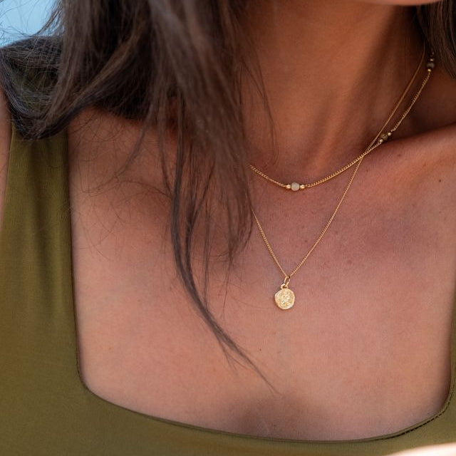 Close-up portrait of a woman wearing a mini St. Christopher necklace