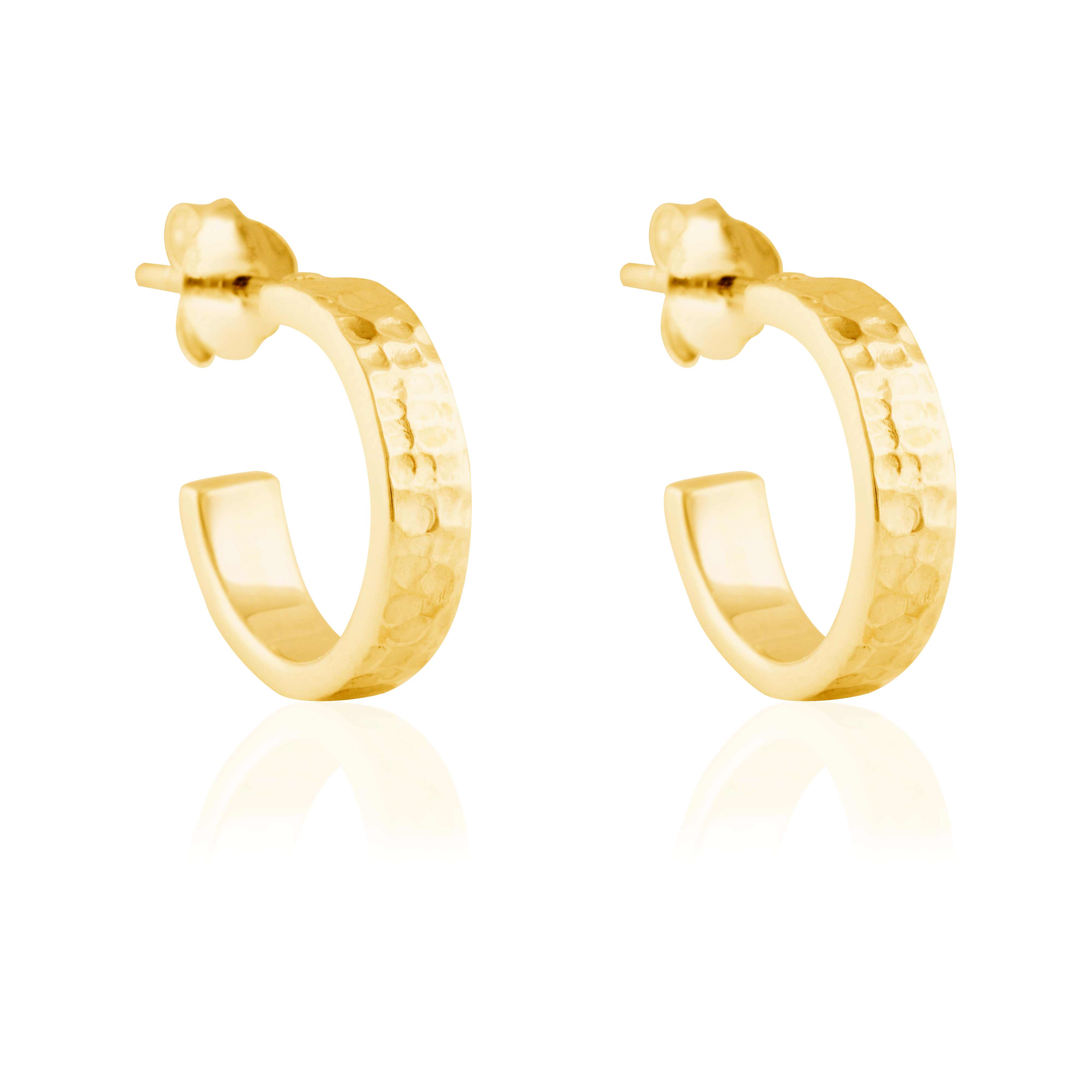 Close-up of a pair of hammered gold hoop earrings with post backings on a reflective white background.