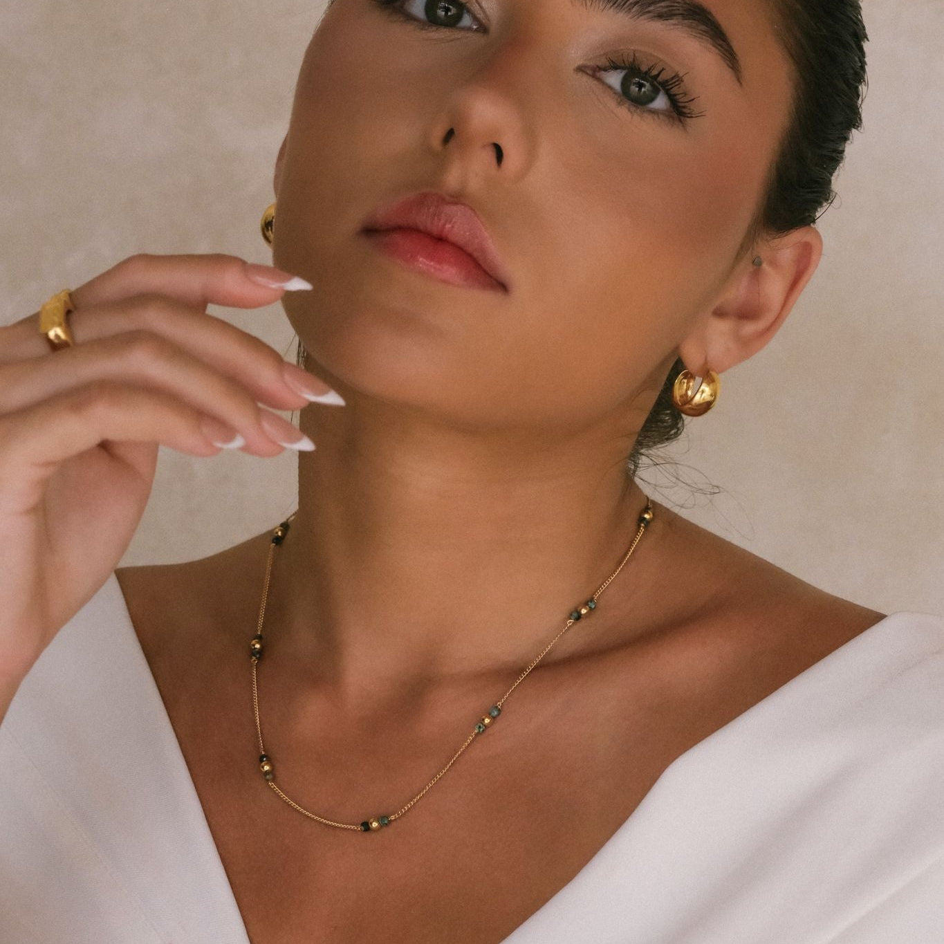 Elegant woman wearing gold necklace combination earrings and rings