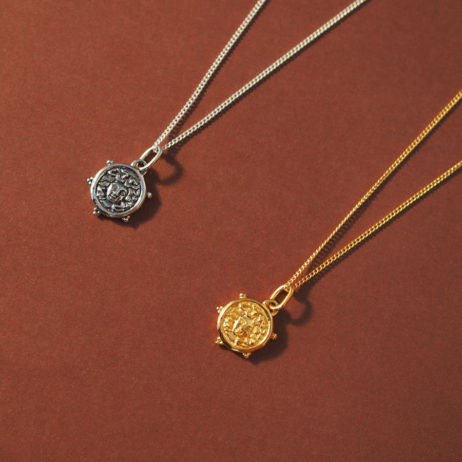 Flat lay of Mini Medusa charm gold and silver