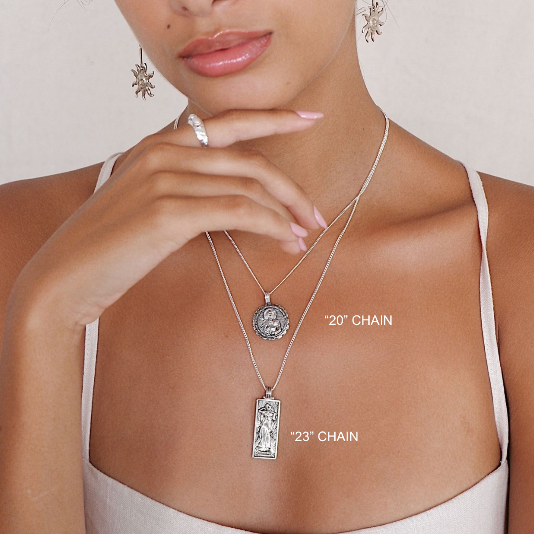 Woman wearing a silver necklace with pendant, close-up on neck and chest.