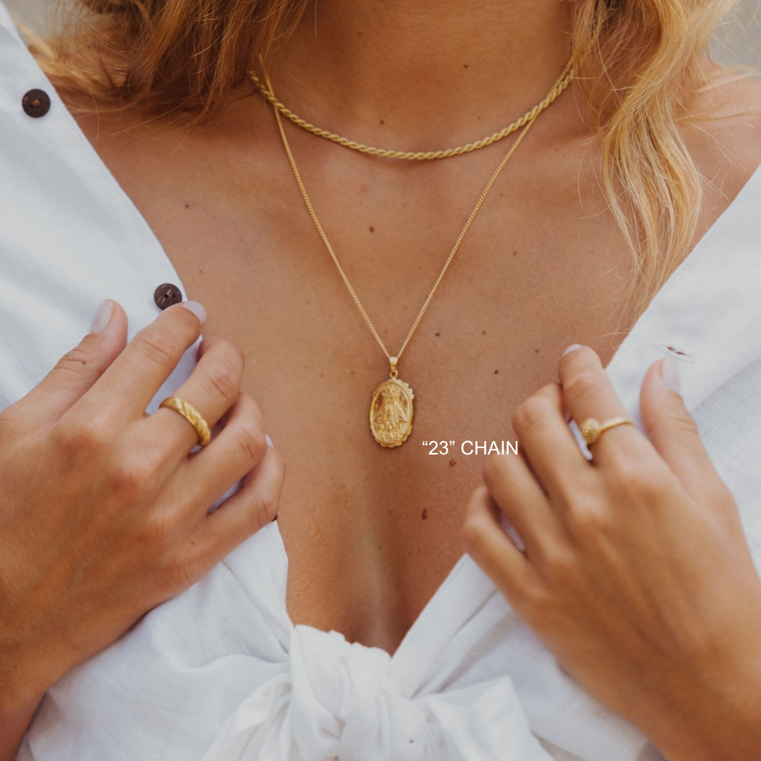 Gold necklace with pendant worn by a person, close-up view.