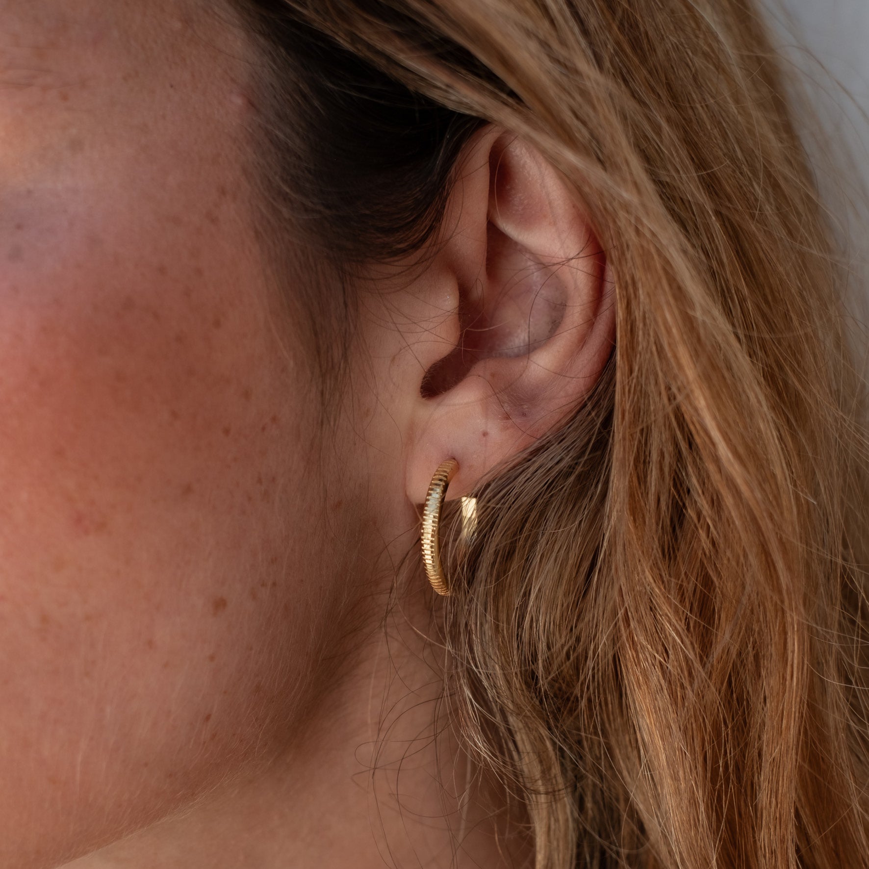 The MET Stripe Thin Earrings 18mm - Gold worn by a woman