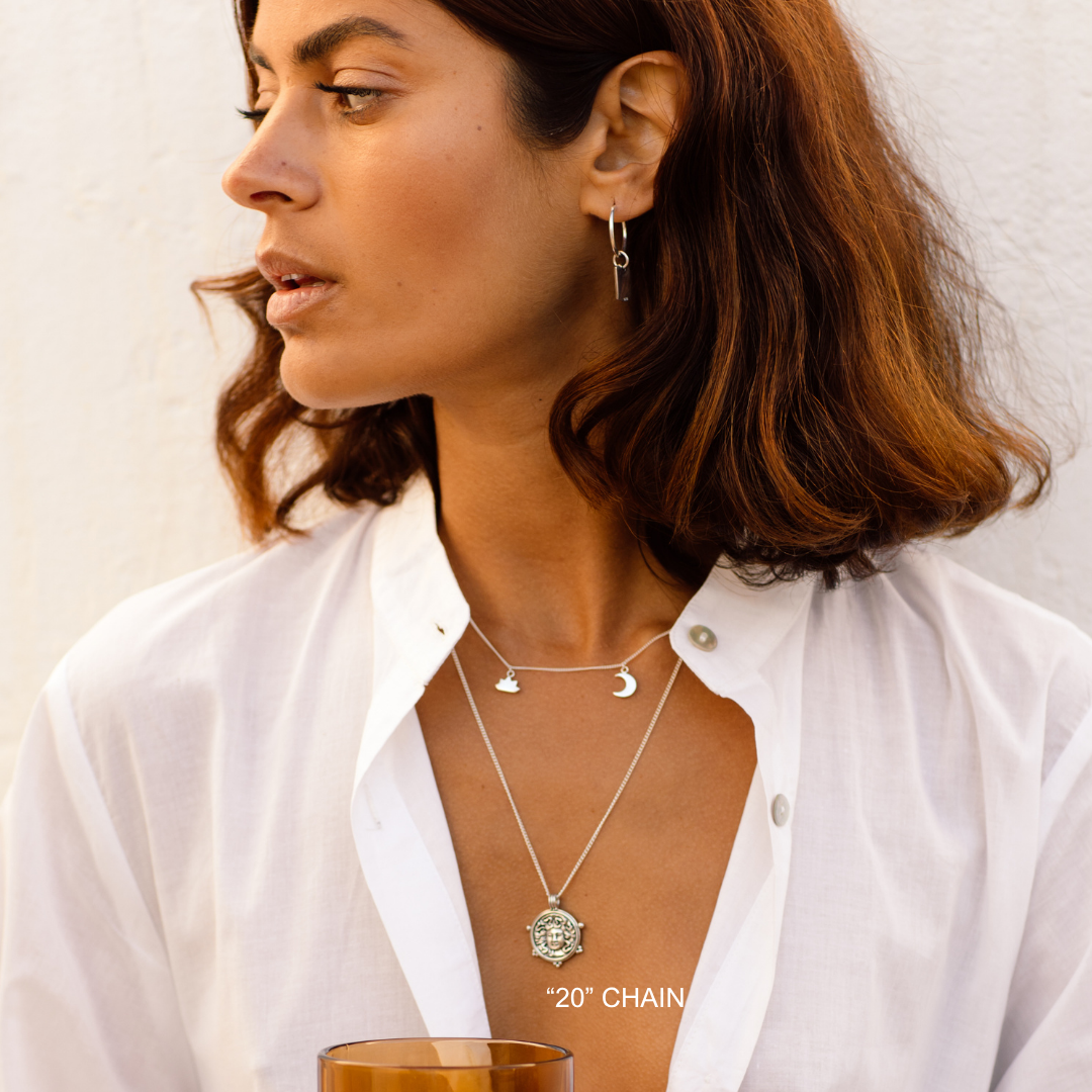Woman wearing a necklace and earrings with a plain background