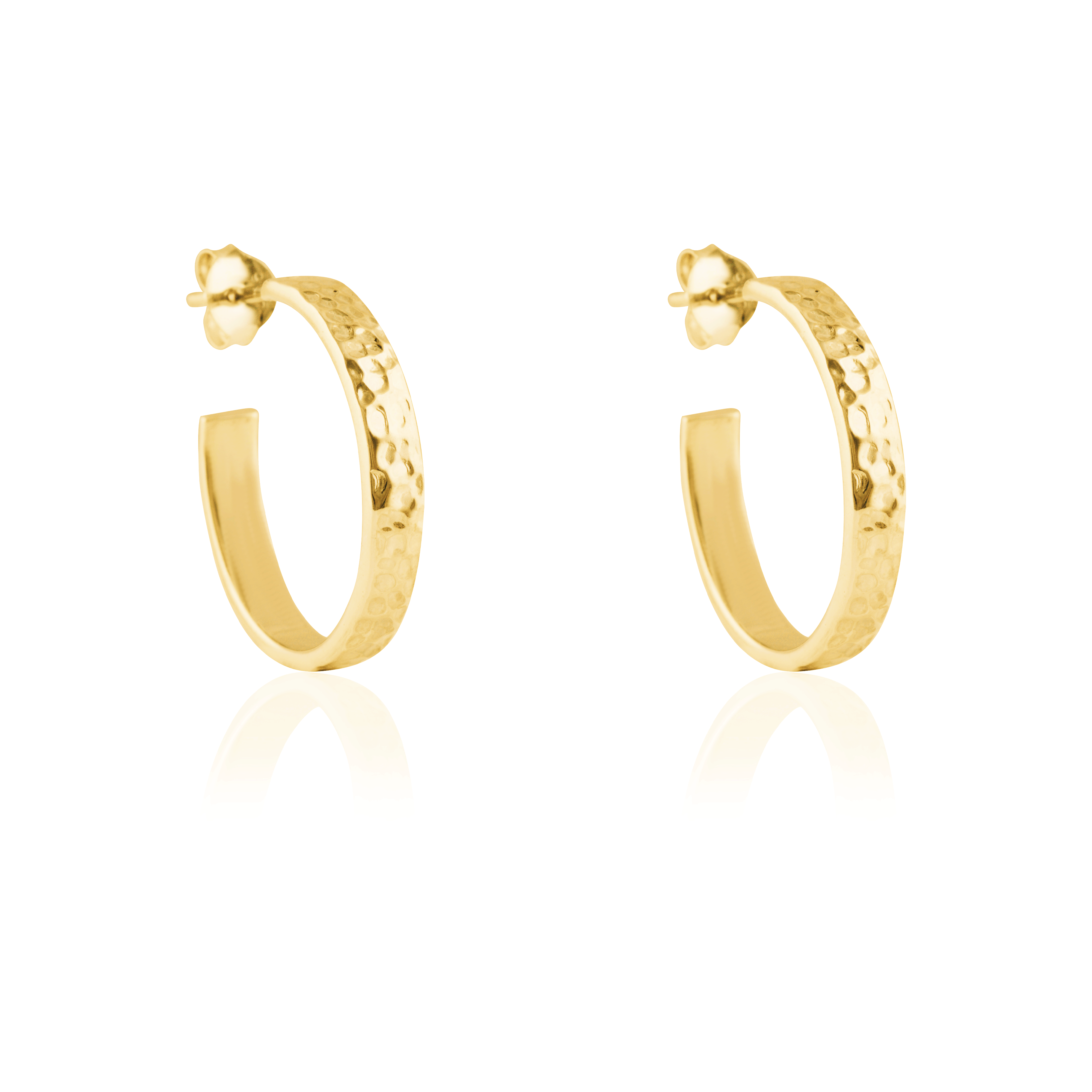 Close-up of a pair of hammered gold hoop earrings with post backings on a reflective white background.