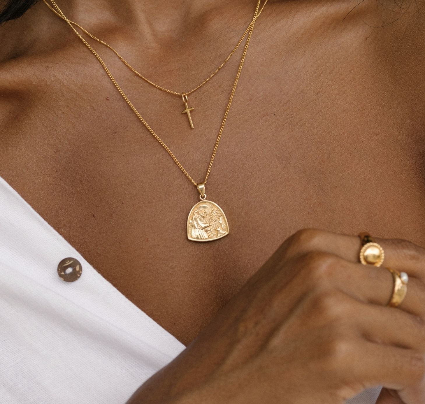 a woman with coconut white shirts wearing St Assisi necklace gold and mini Madonna cross necklace gold