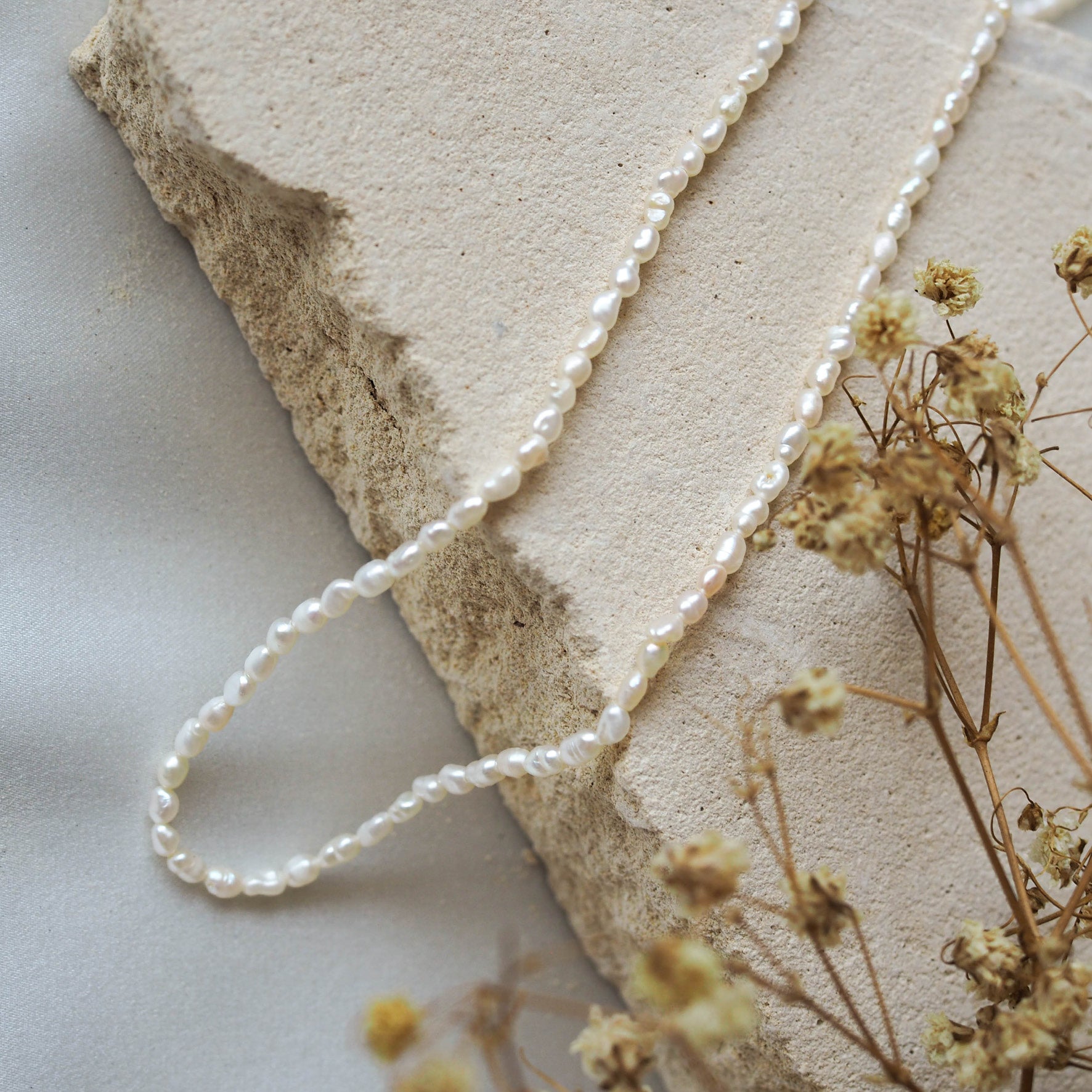 Timeless Mini Pearl Necklace - Silver displayed on beige stone