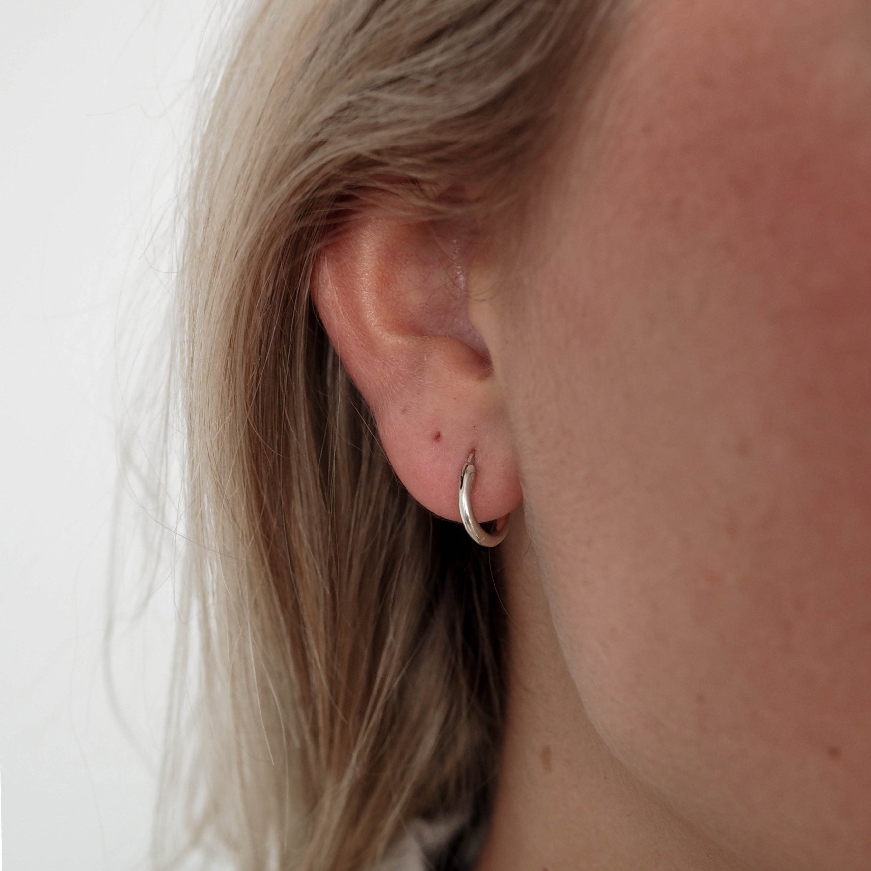 a woman with blonde hair wearing signature hoops petite 10mm gold