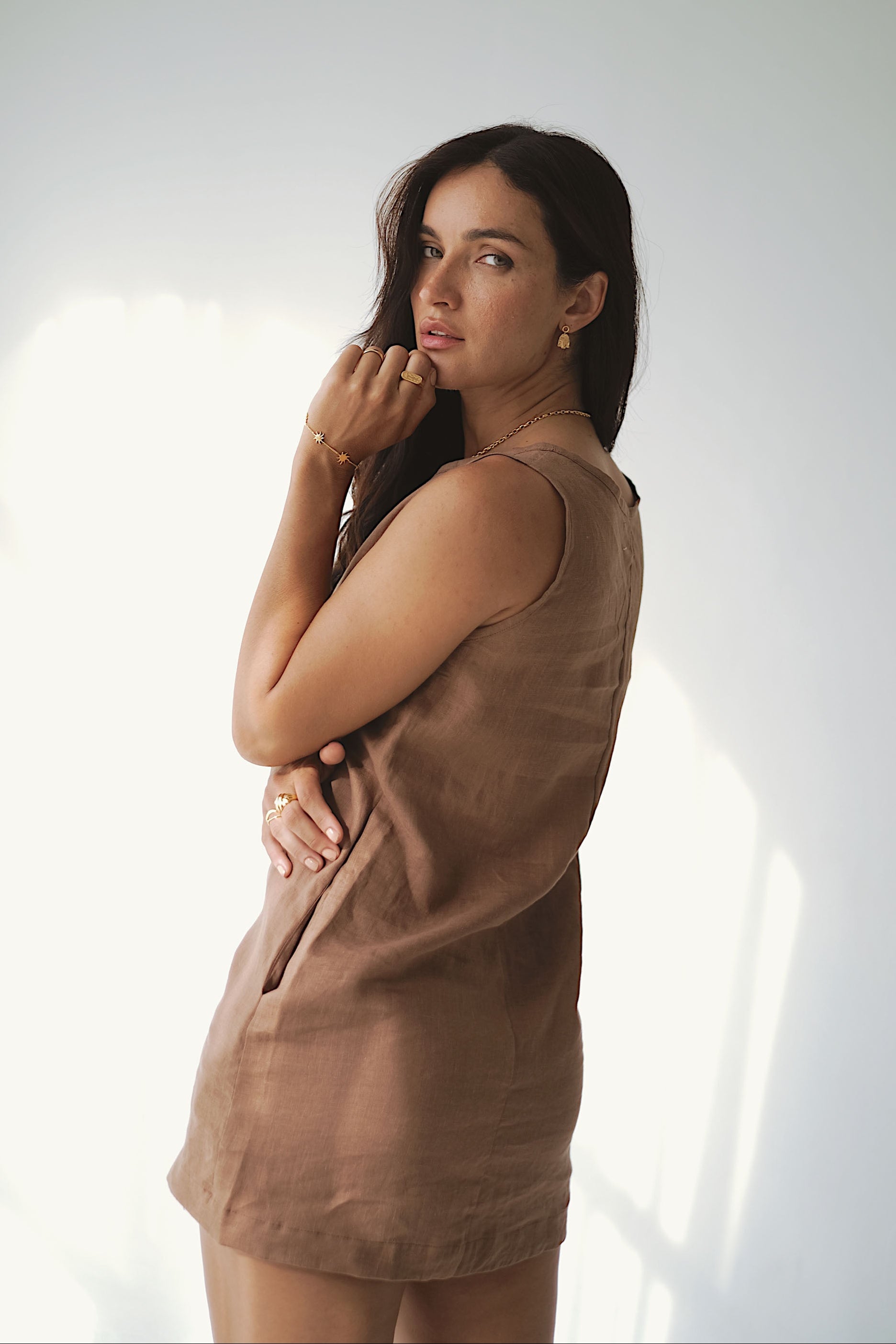 Woman wearing a brown sleeveless dress against a white background