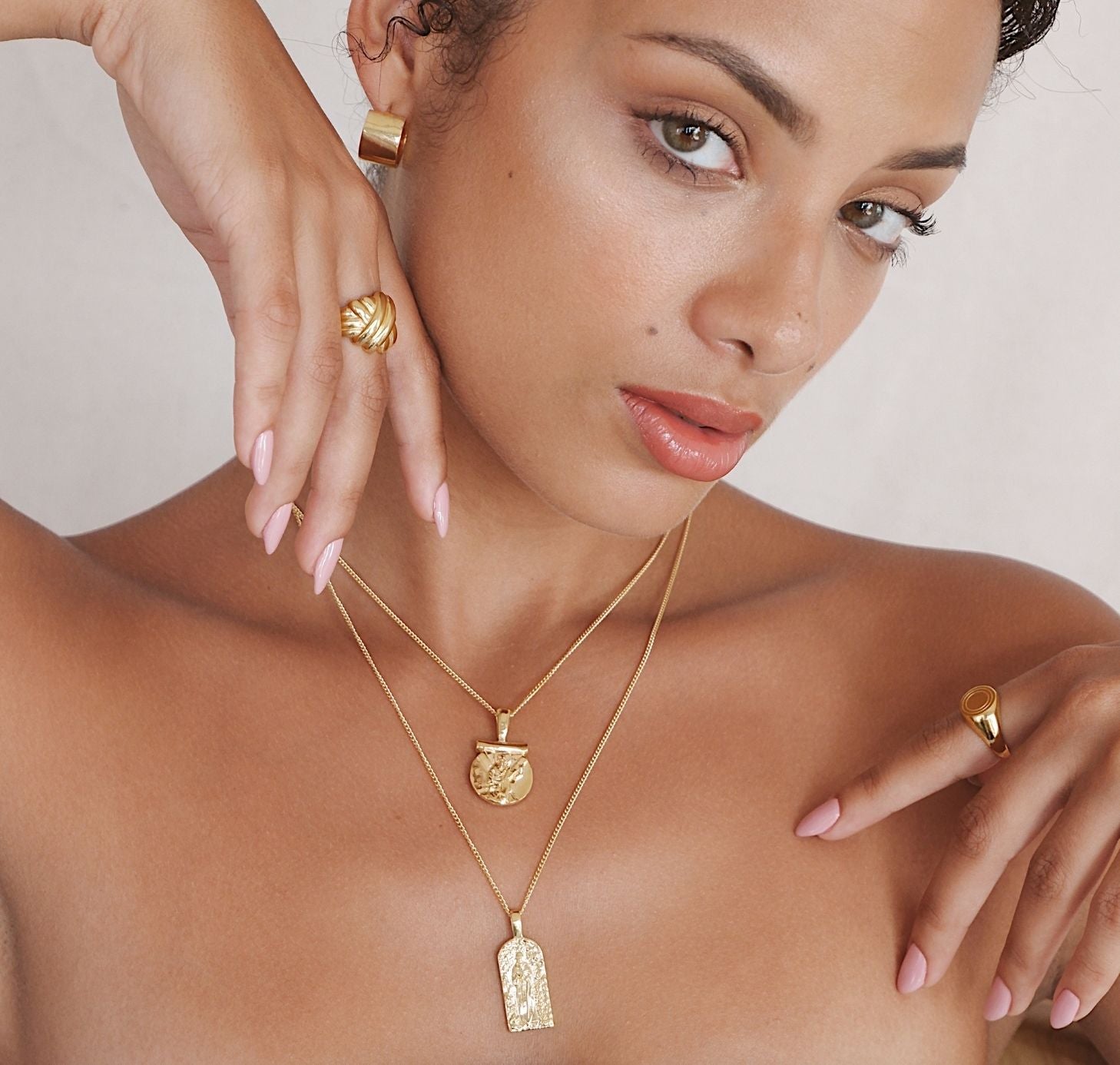 a woman wearing jewelry gold necklaces, ring and earrings gold