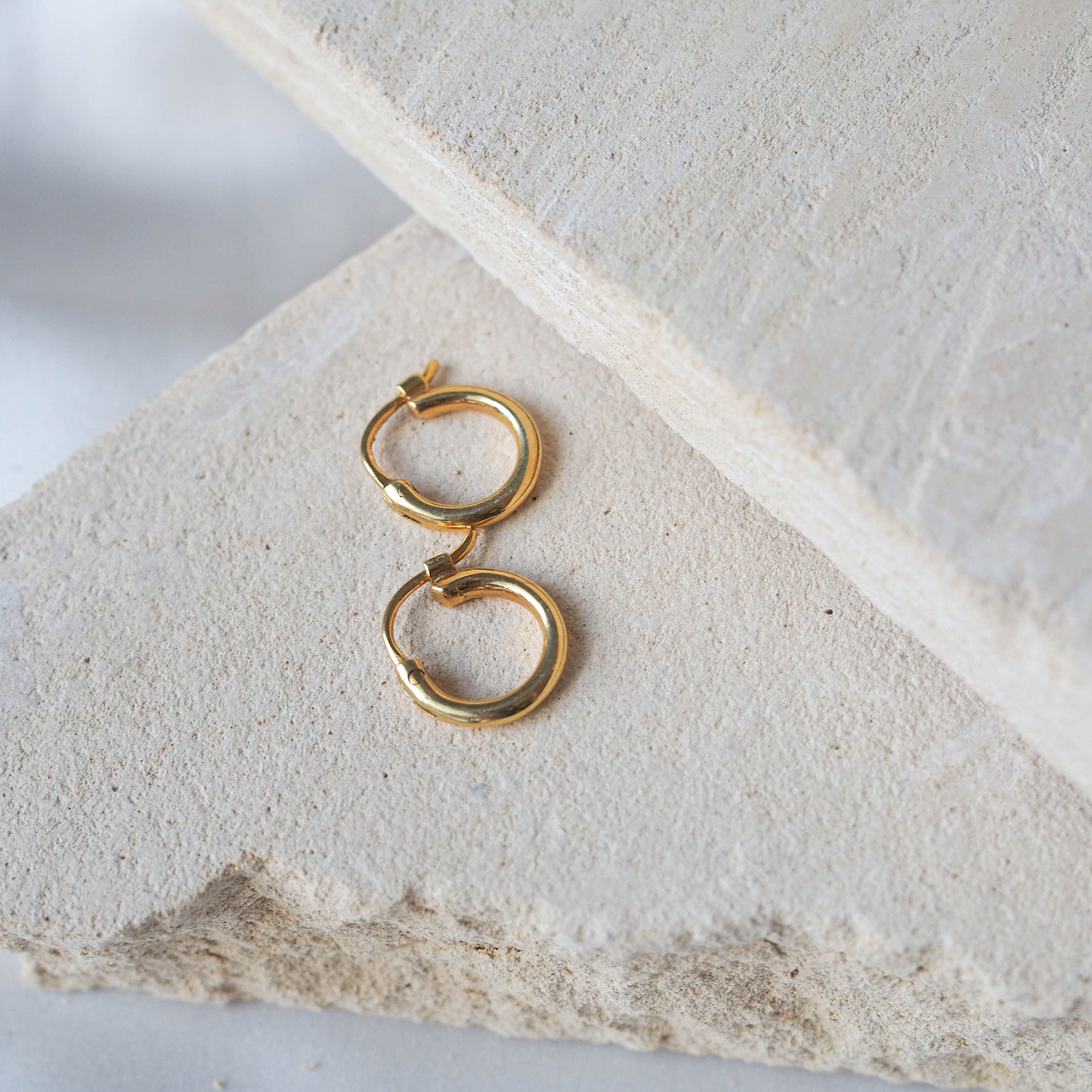 Signature Hoops 10mm Petite - Gold displayed on beige stone