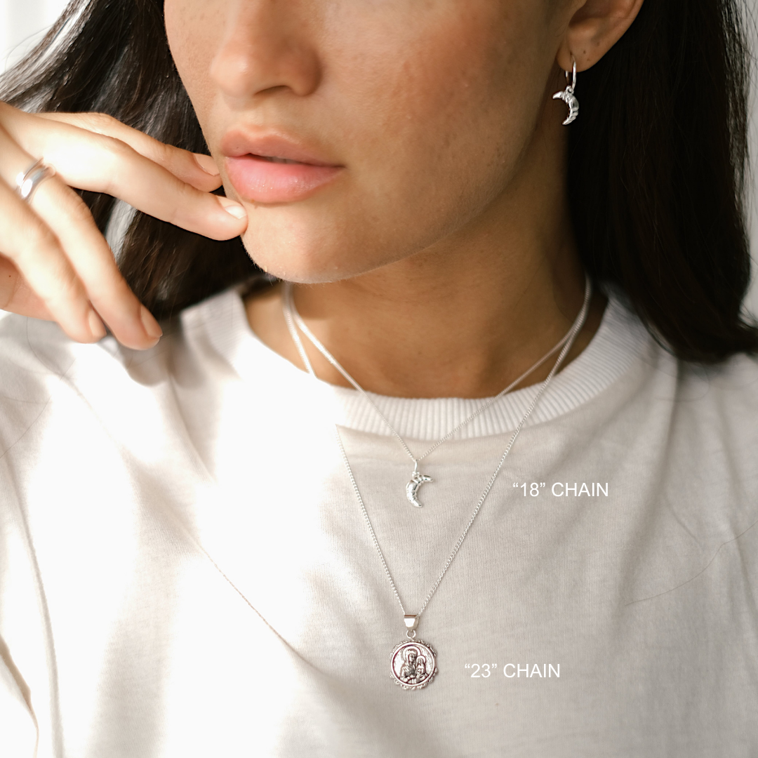 Close-up of a person wearing necklaces with chain lengths labeled, against a neutral background.