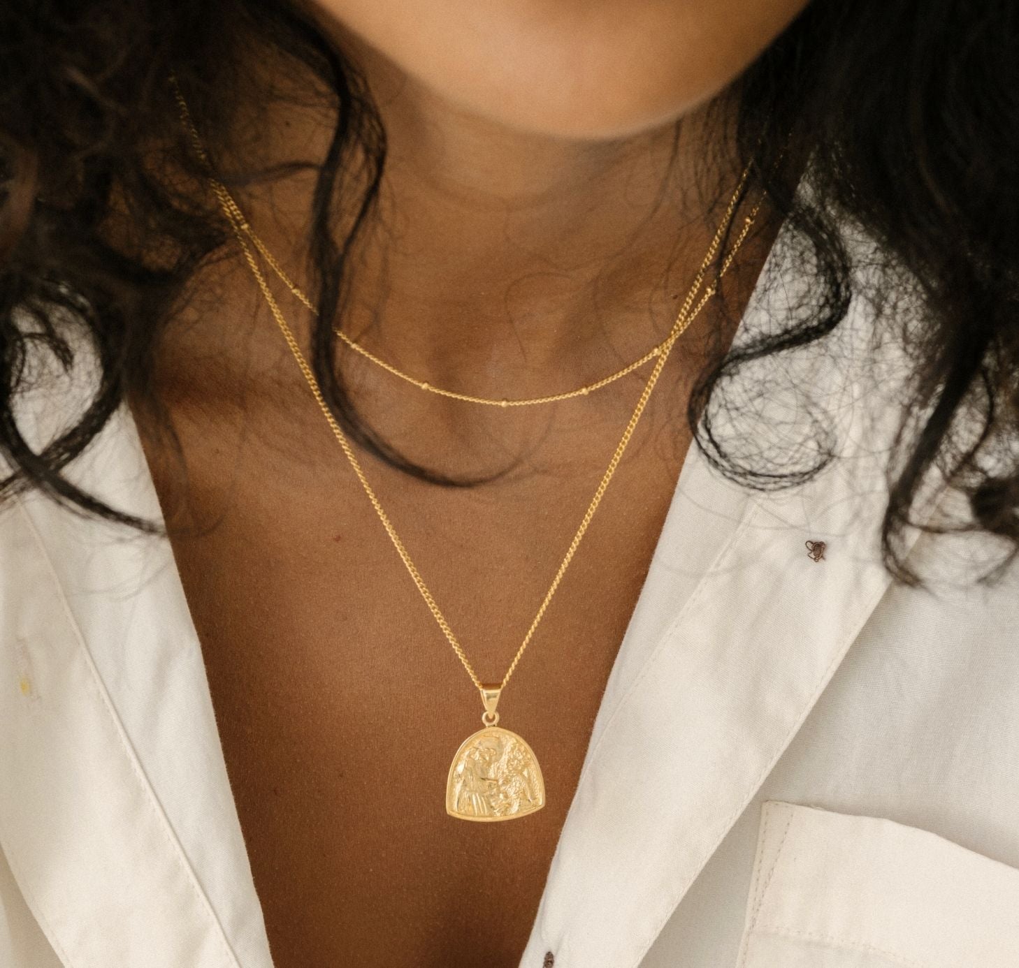 a woman with white linen shirts wearing St Assisi necklace gold and chain ball gold