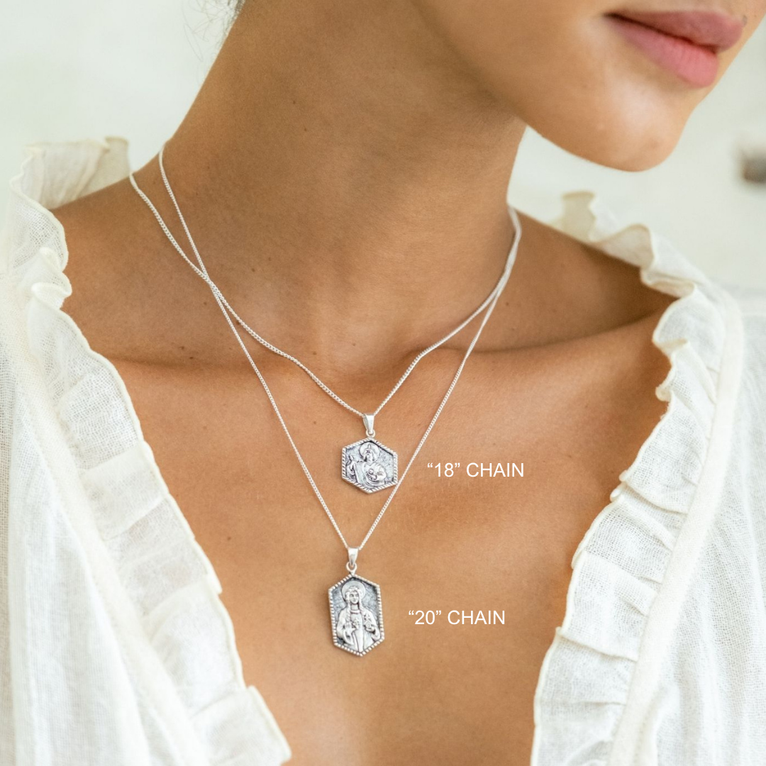 Silver necklace with two chain lengths displayed on a person wearing a white blouse.