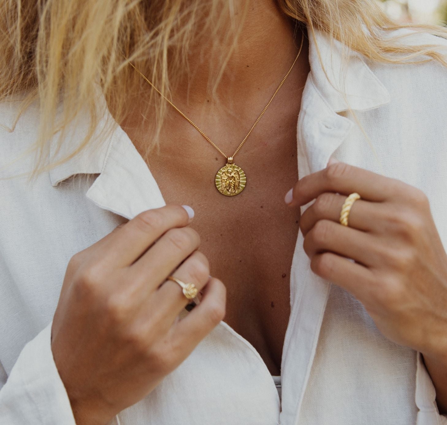 a woman open her collar neck wearing St Gabriel - Archangel Saint of Communication gold