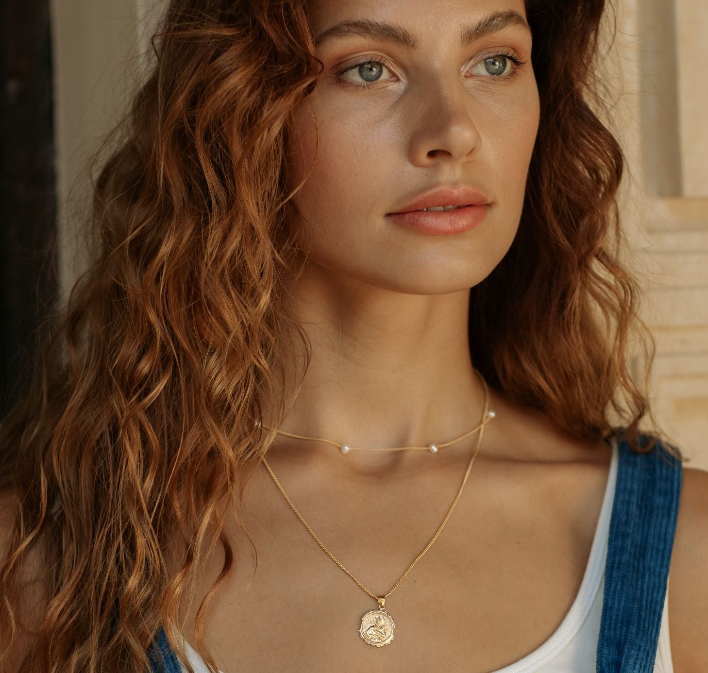 a woman with lake blue jumpsuit wearing St Gerard and The Maisy chain pearl necklace gold