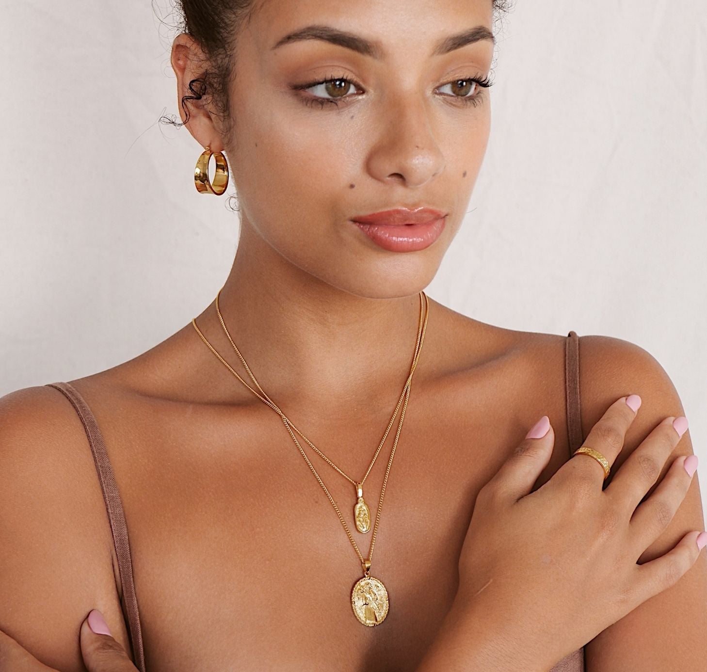 a woman wearing two necklaces gold