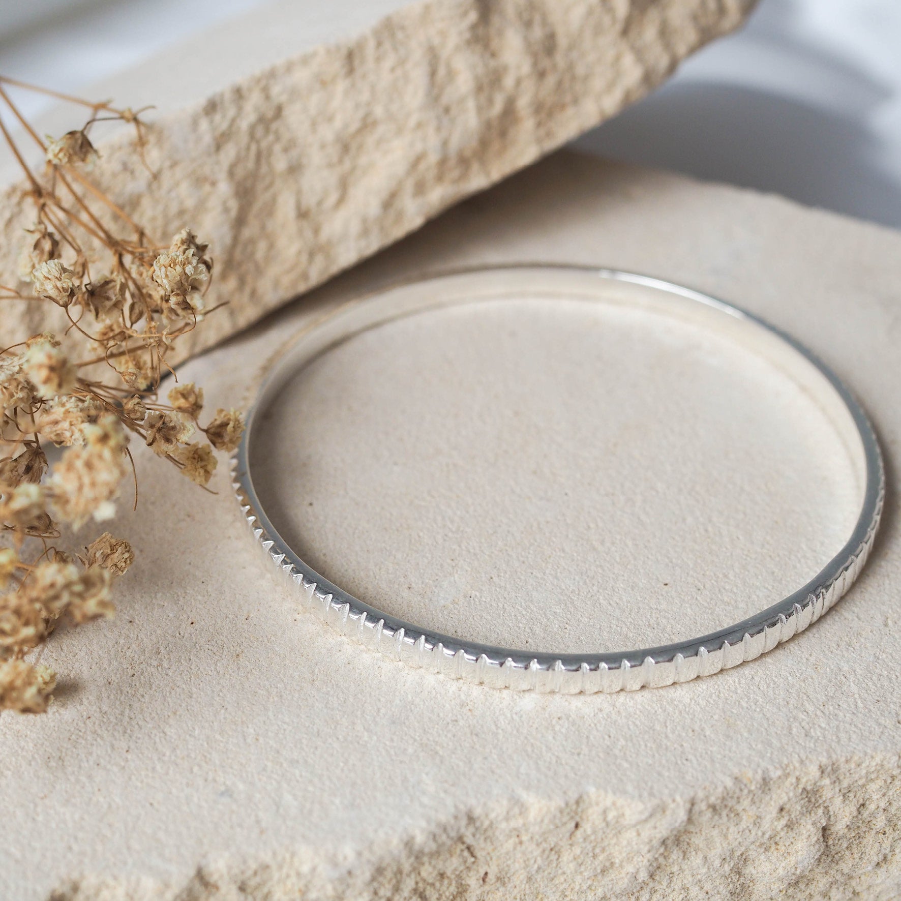 The MET Stripe Bracelet - Silver 4mm displayed on beige stone