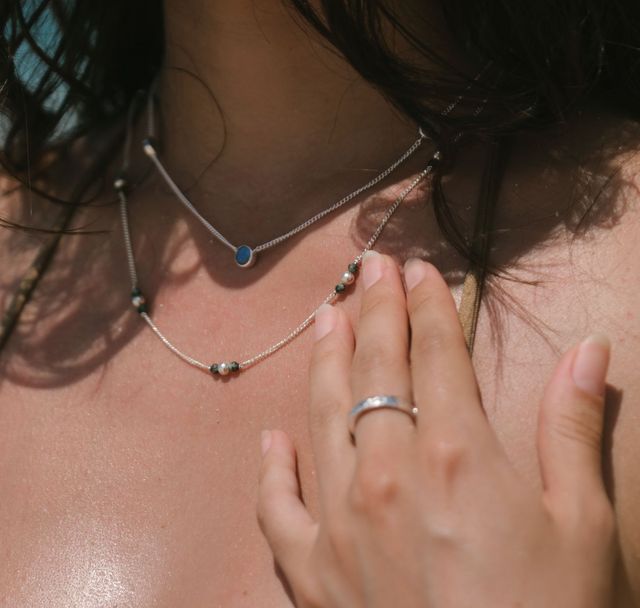 a woman touching her layered necklace