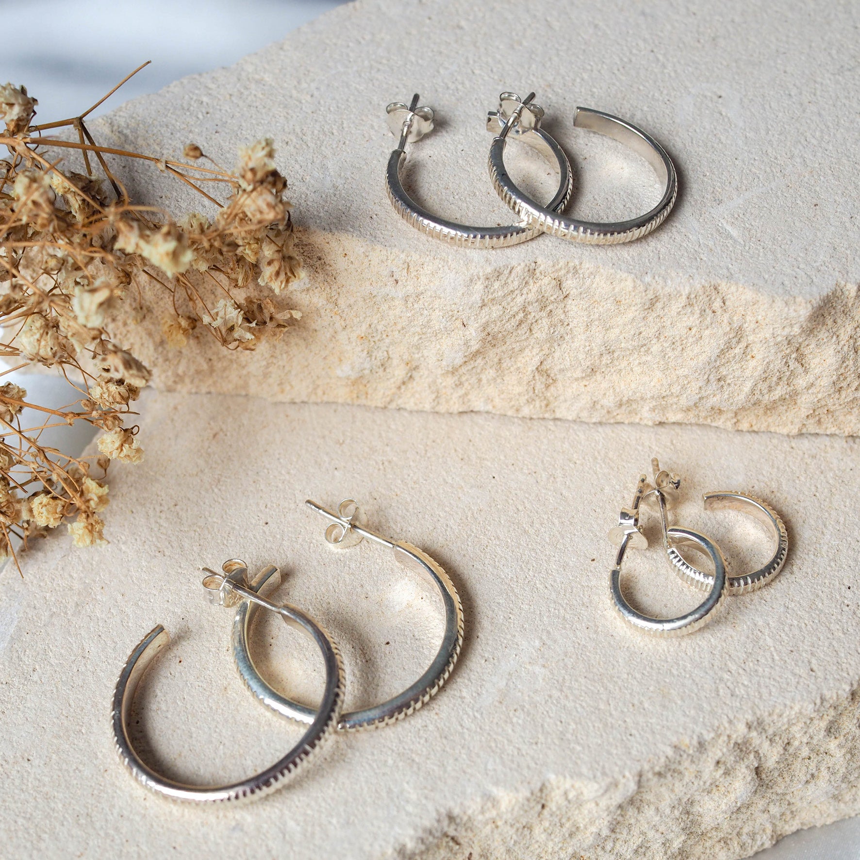 The MET Stripe Thin Earrings Silver in three sizes on beige stone and dried flowers