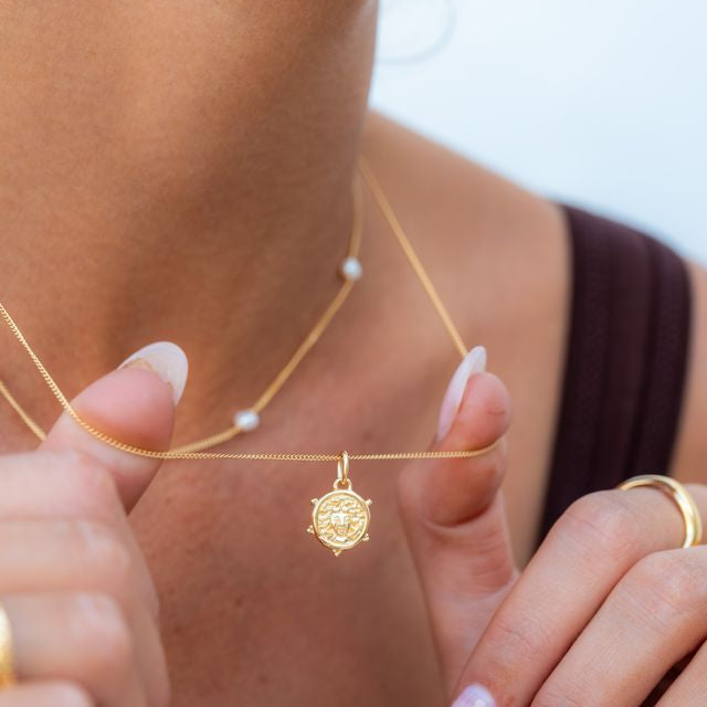 Woman wearing a delicate mini Medusa gold necklace