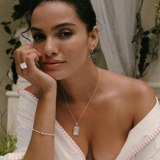 Woman wearing a necklace with a pendant, sitting outdoors