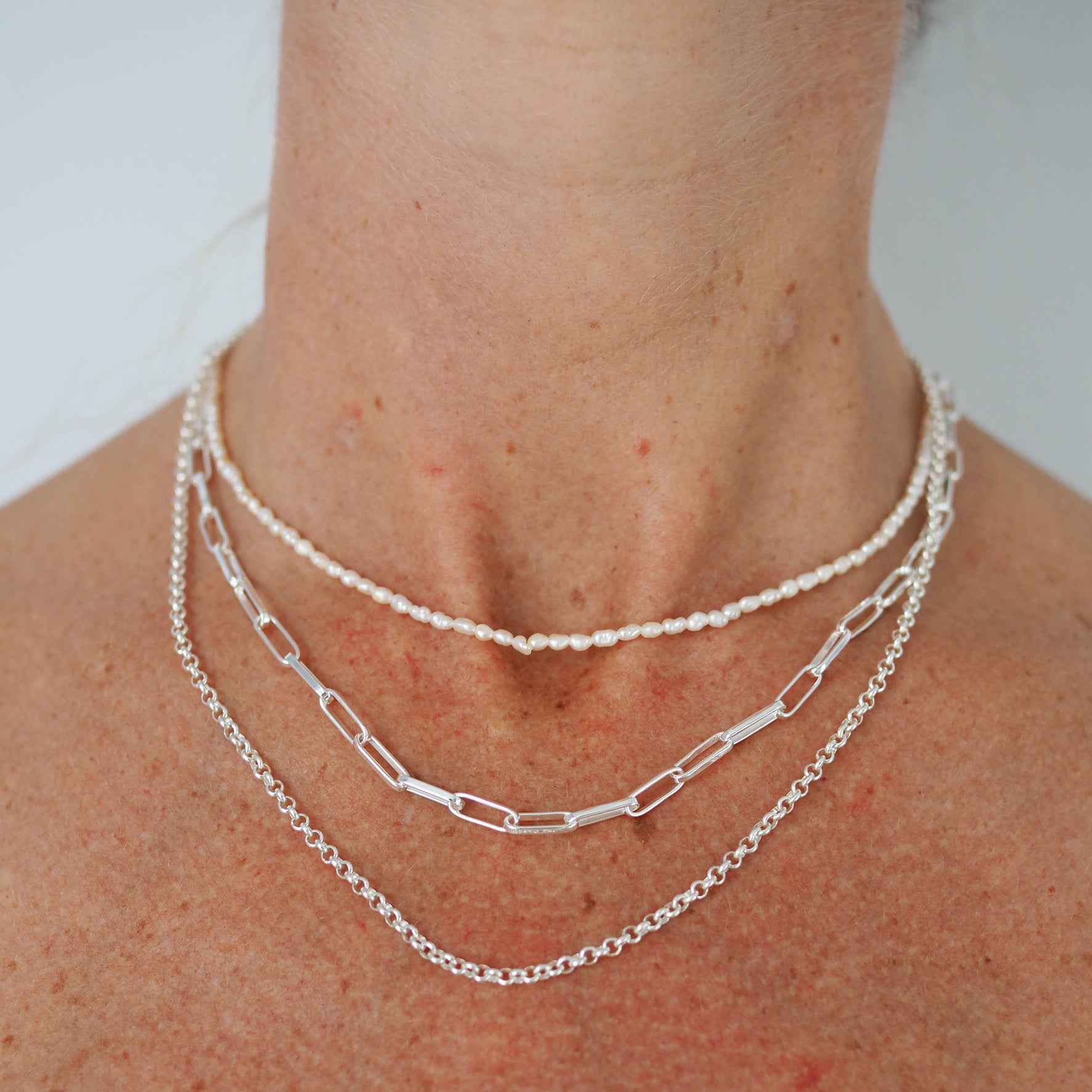 a woman wearing multiple silver necklaces on her
