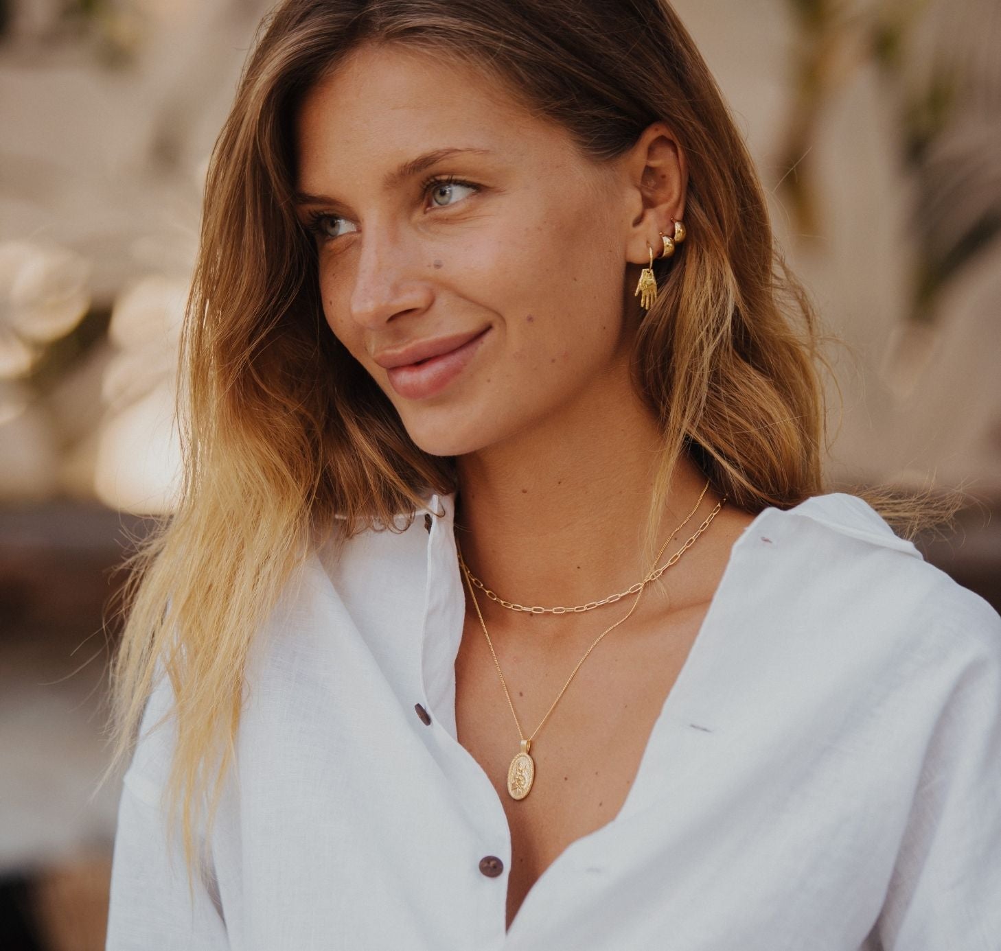 a woman wearing coconut white shirts and jewelry gold