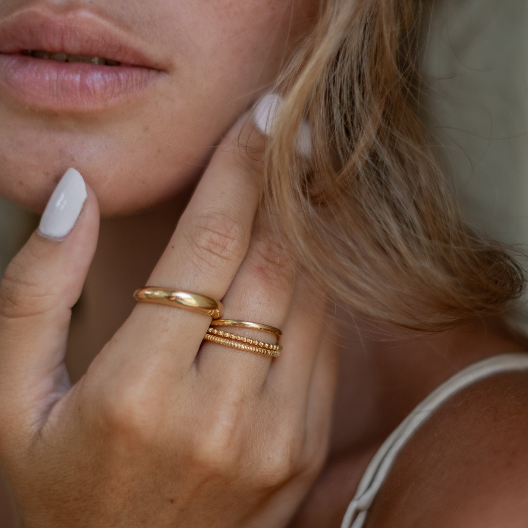 a woman wearing multiple rings gold on her