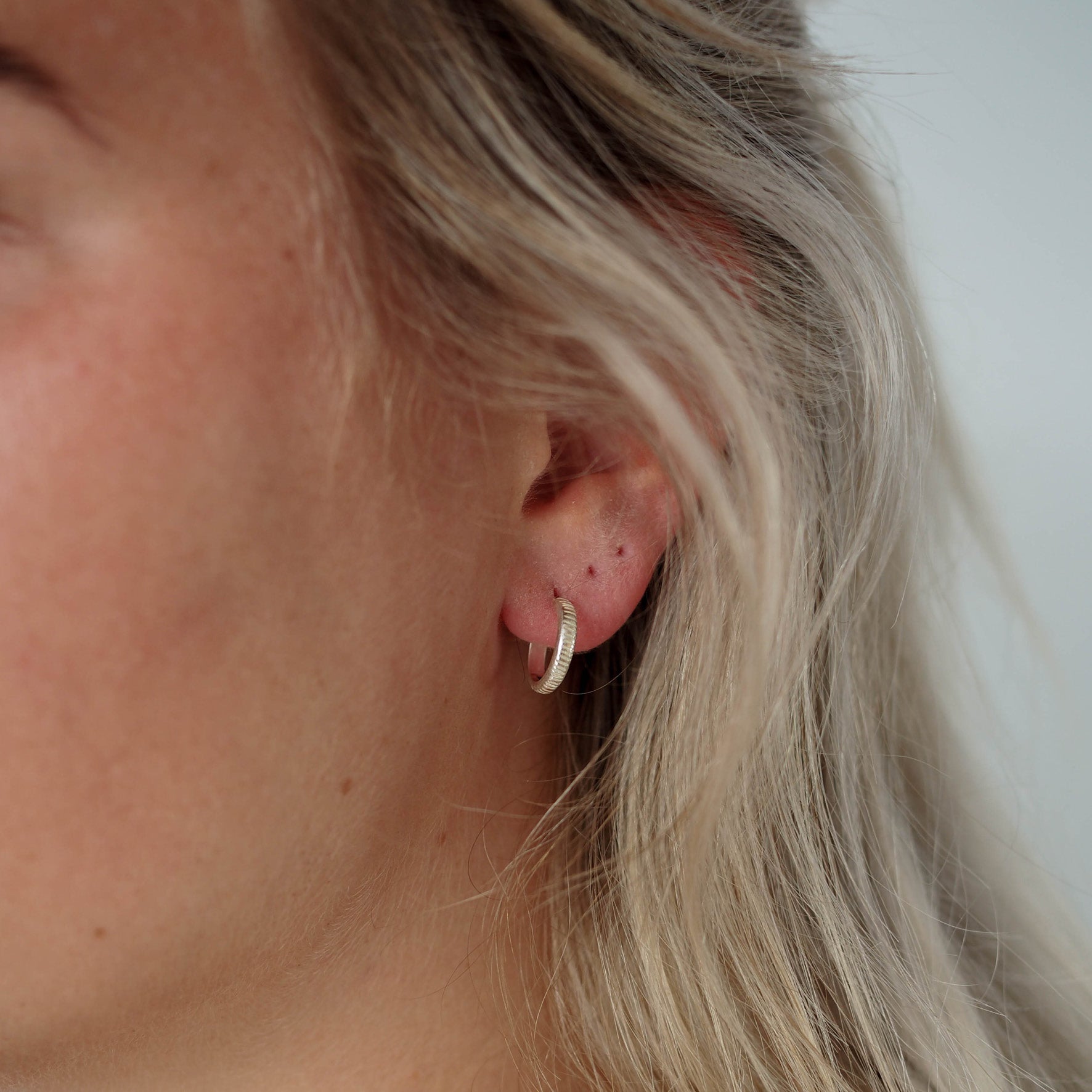 a woman with blonde hair wearing silver earring