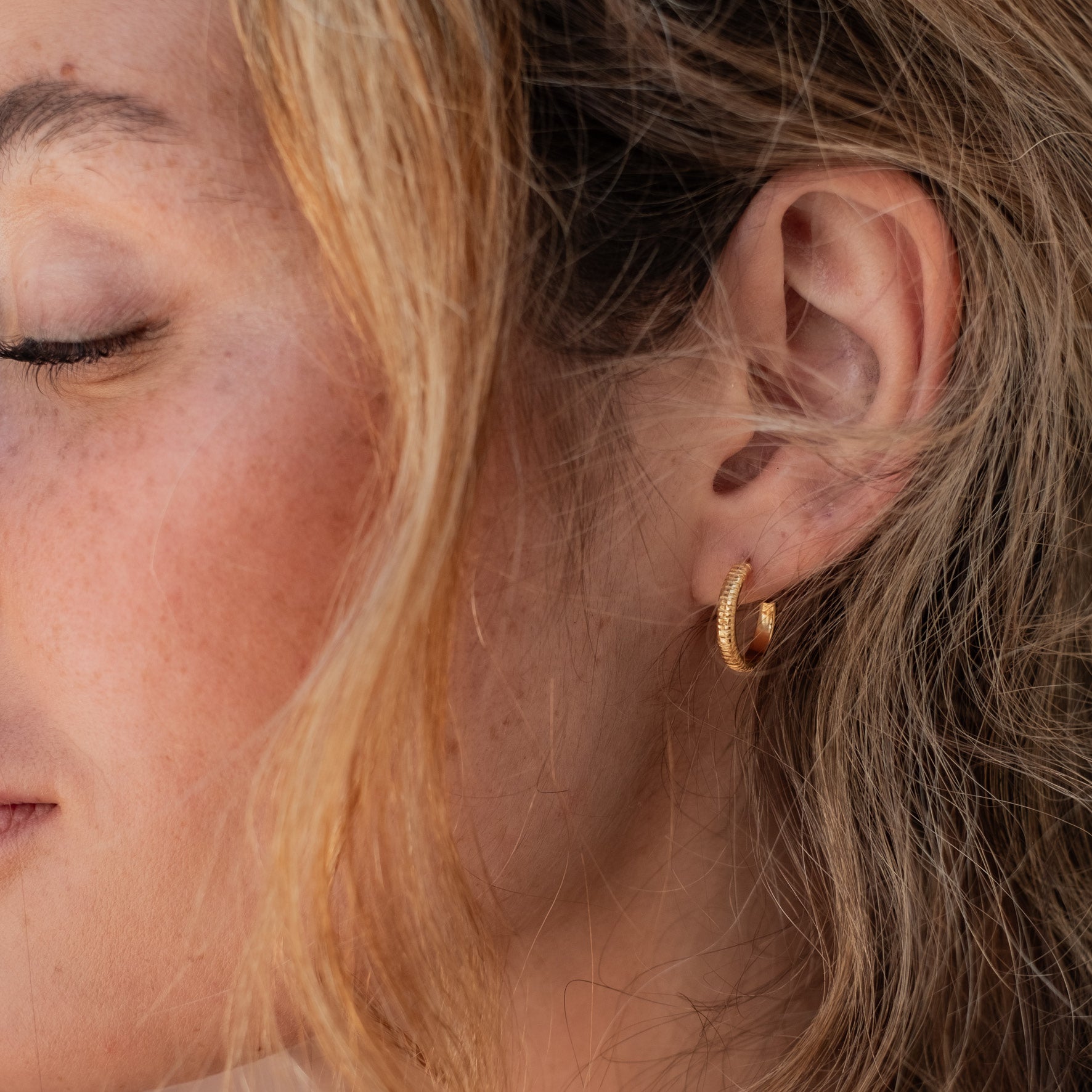 The MET Stripe Thin Earrings 12mm - Gold on a woman with blonde hair