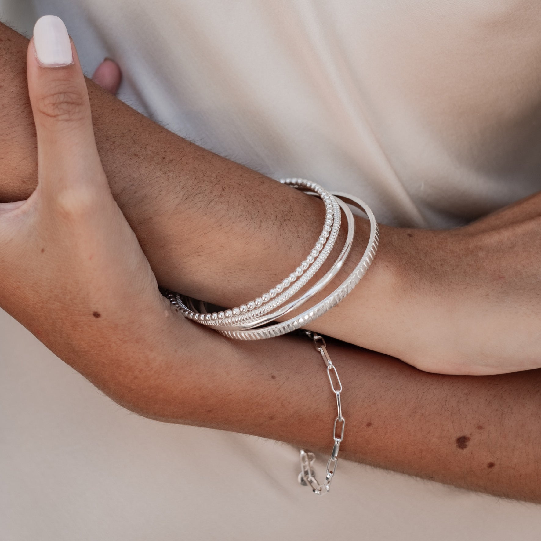 a woman with white dress wearing multiple bracelets silver on her