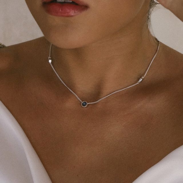 a woman with silver chain necklace with a round gemstone charm