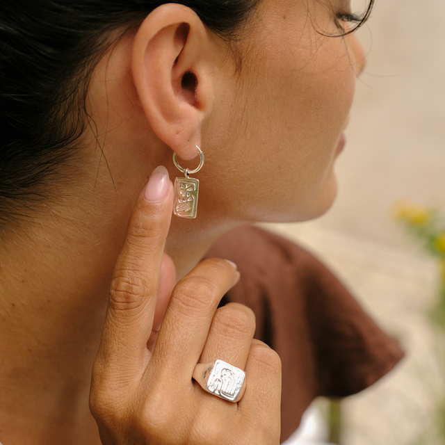 Close-up of silver jewelry worn with a cocoa-colored dress