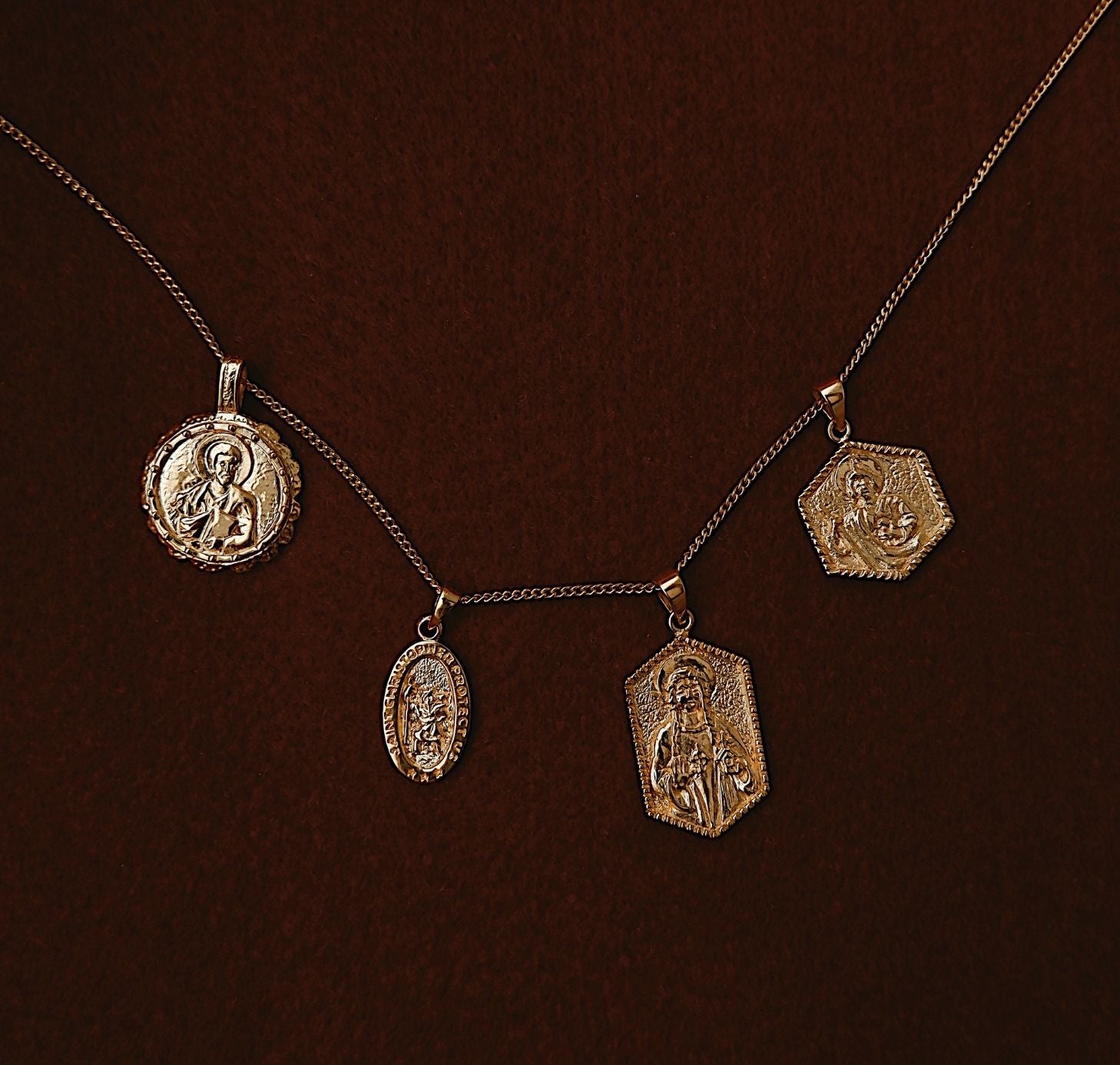 four charms gold flat lay in red fabric