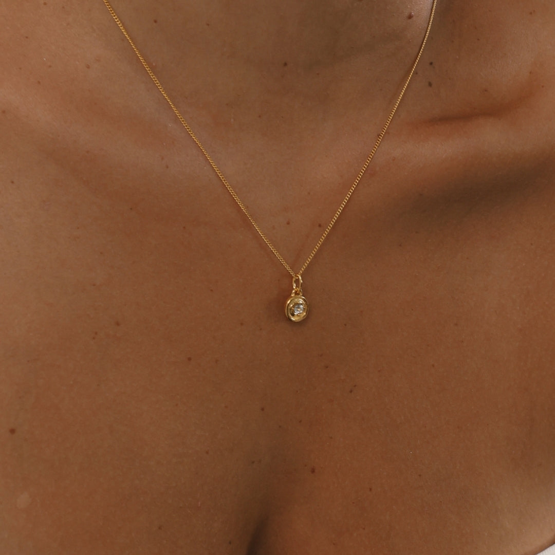 Gold necklace with a small pendant on a person's neck