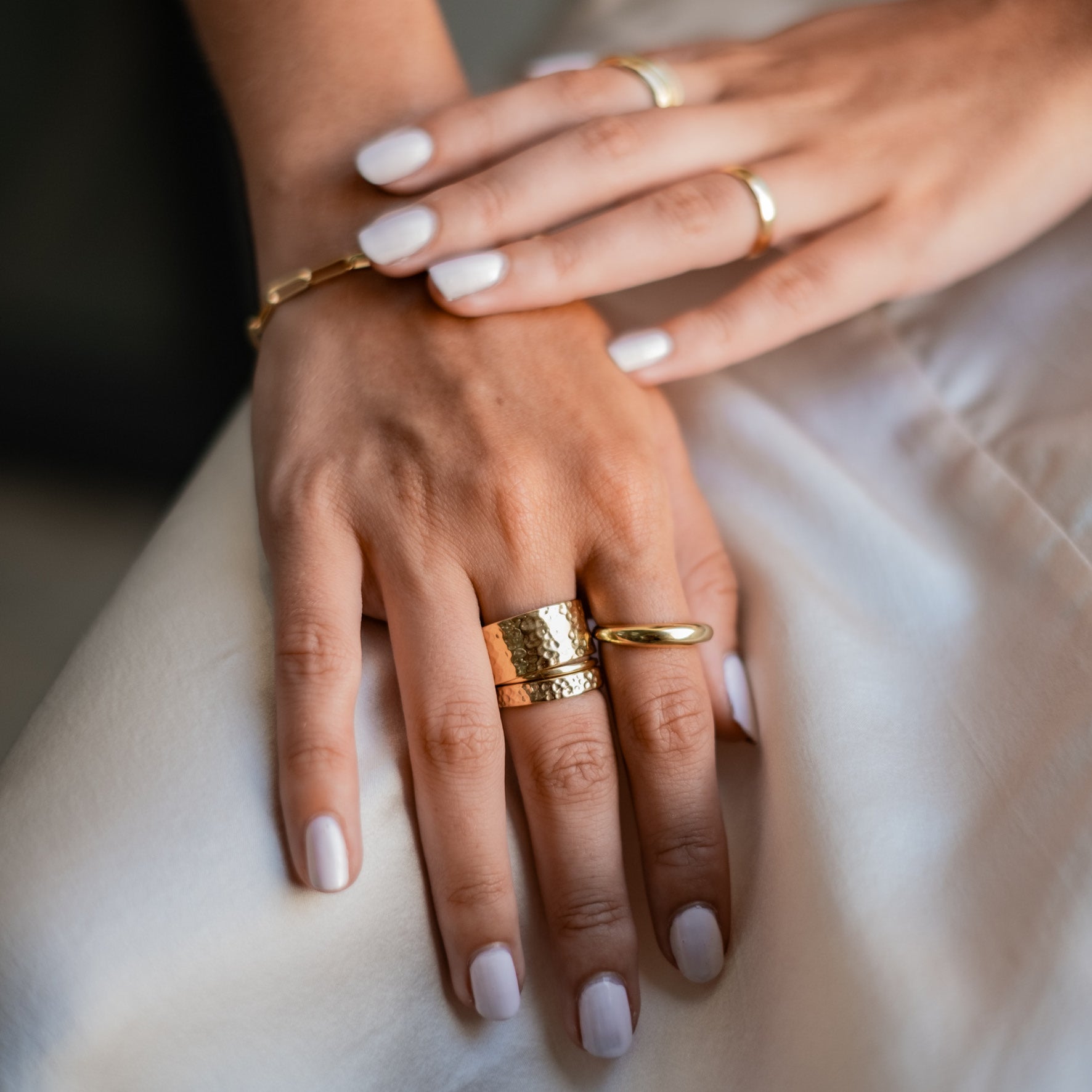 Multiple gold rings with a hammered texture on a woman's fingers.