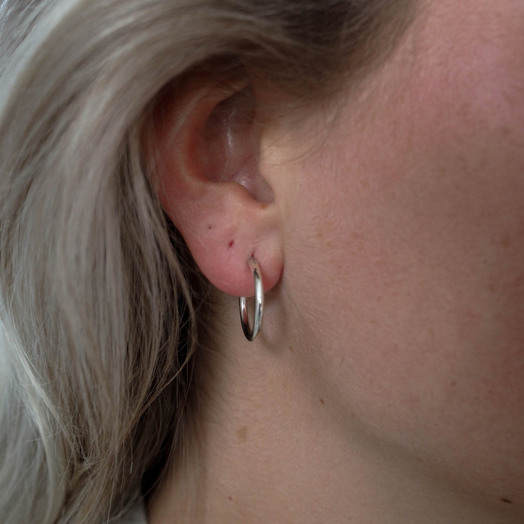 a woman wearing signature hoops earrings 18mm silver