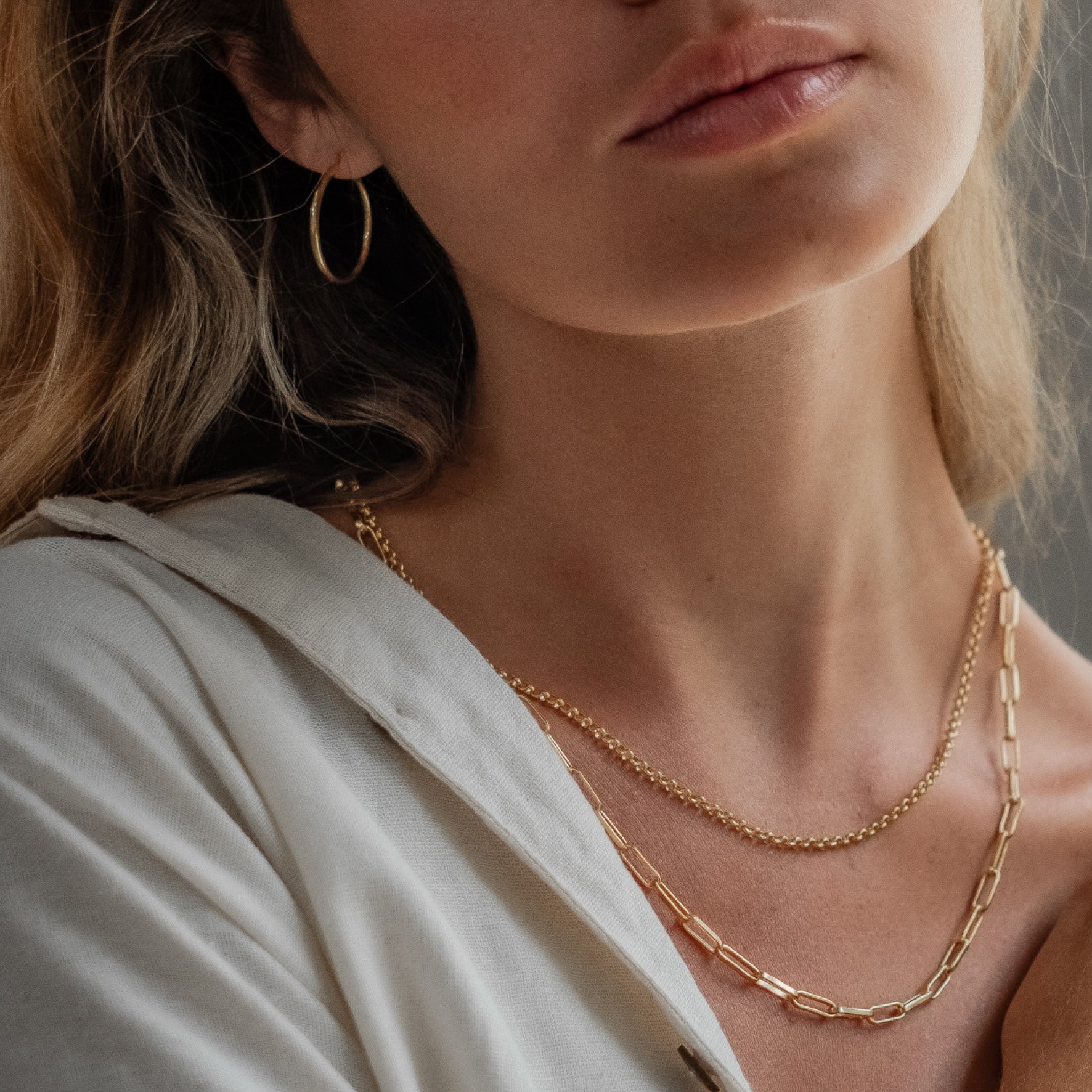 a woman wearing necklace gold and earrings gold