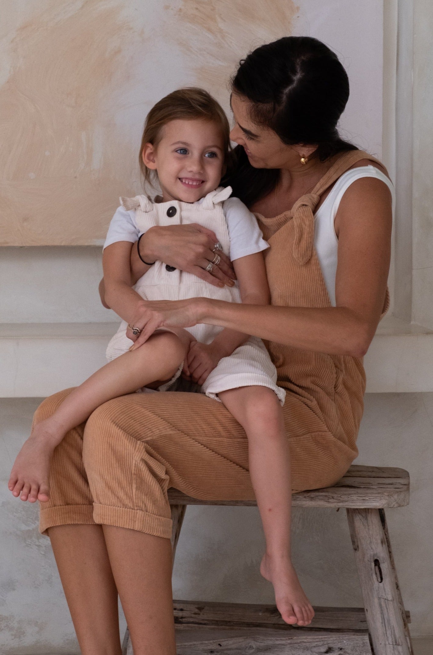 A child with her mother both wearing a overall