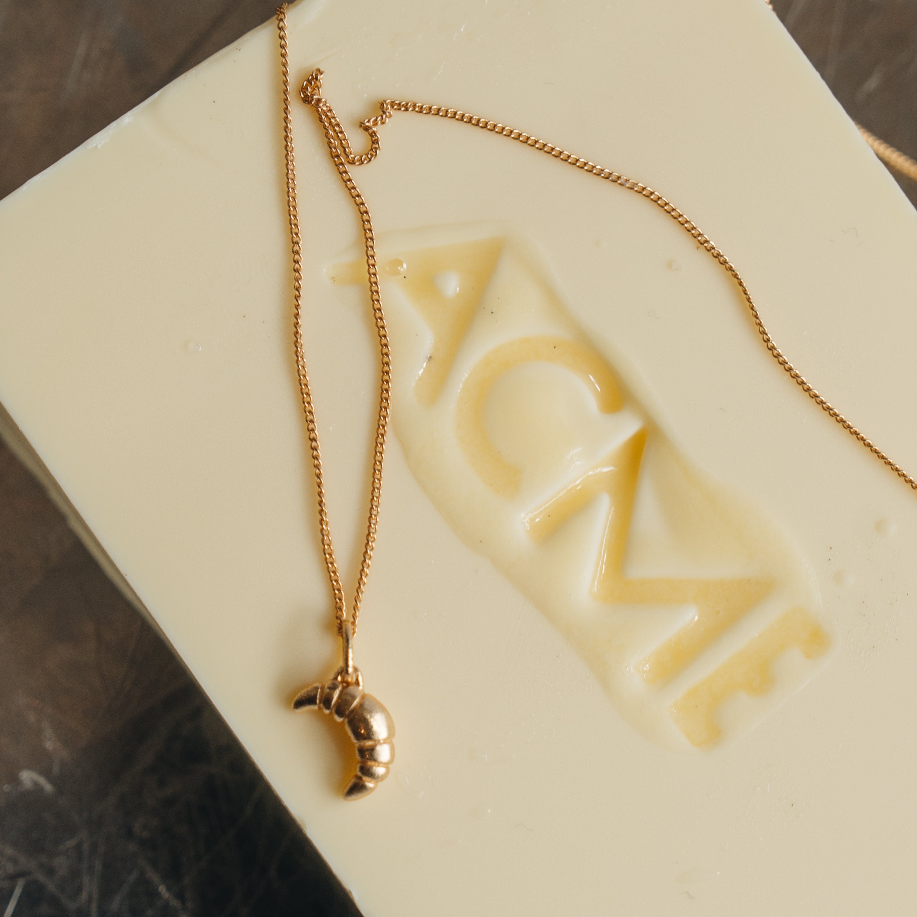 Mini Croissant Necklace in Gold from the ACME x Luna & Rose collection, a dainty croissant-shaped pendant for an elegant and playful touch.