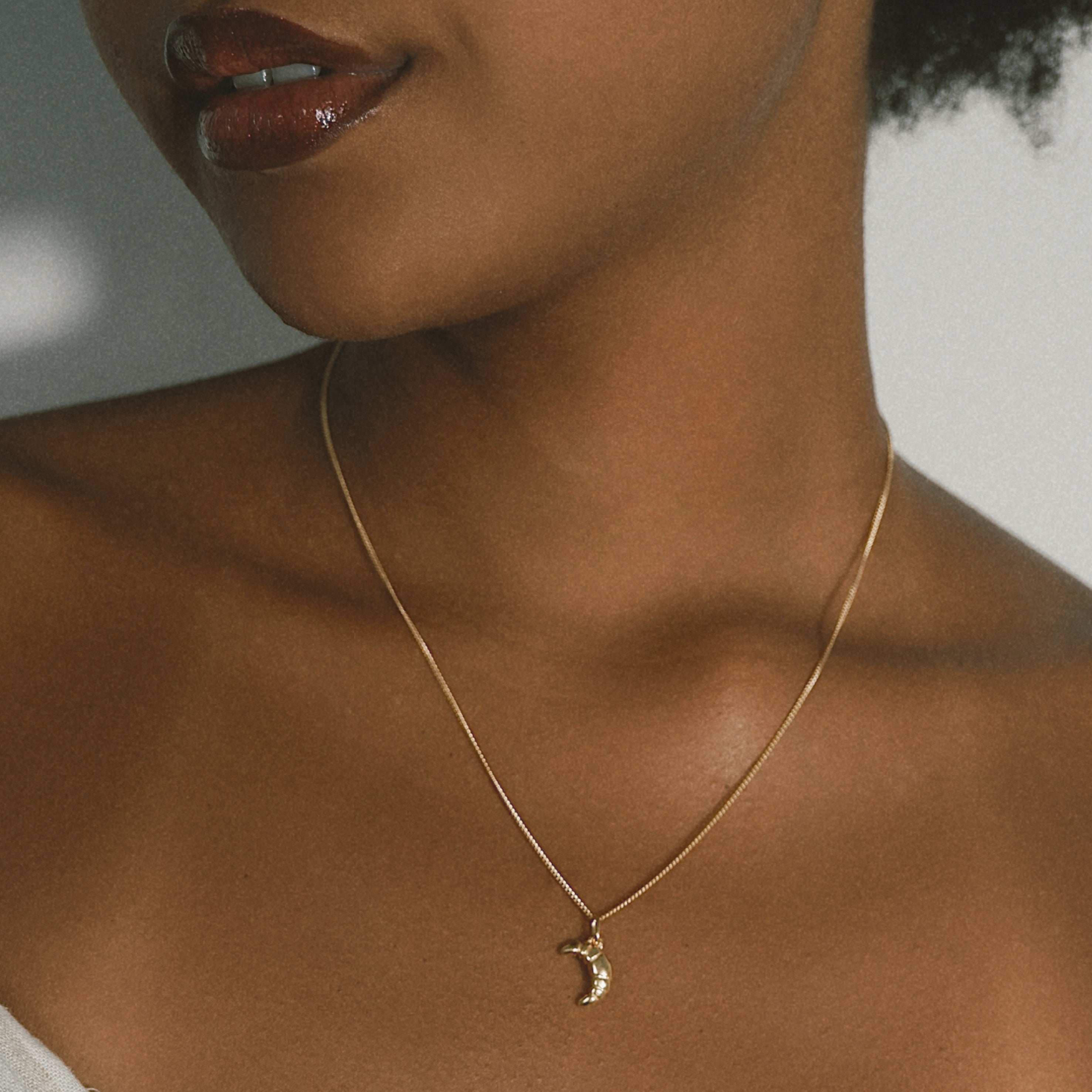 Mini Croissant Necklace in Gold from the ACME x Luna & Rose collection, a dainty croissant-shaped pendant for an elegant and playful touch.
