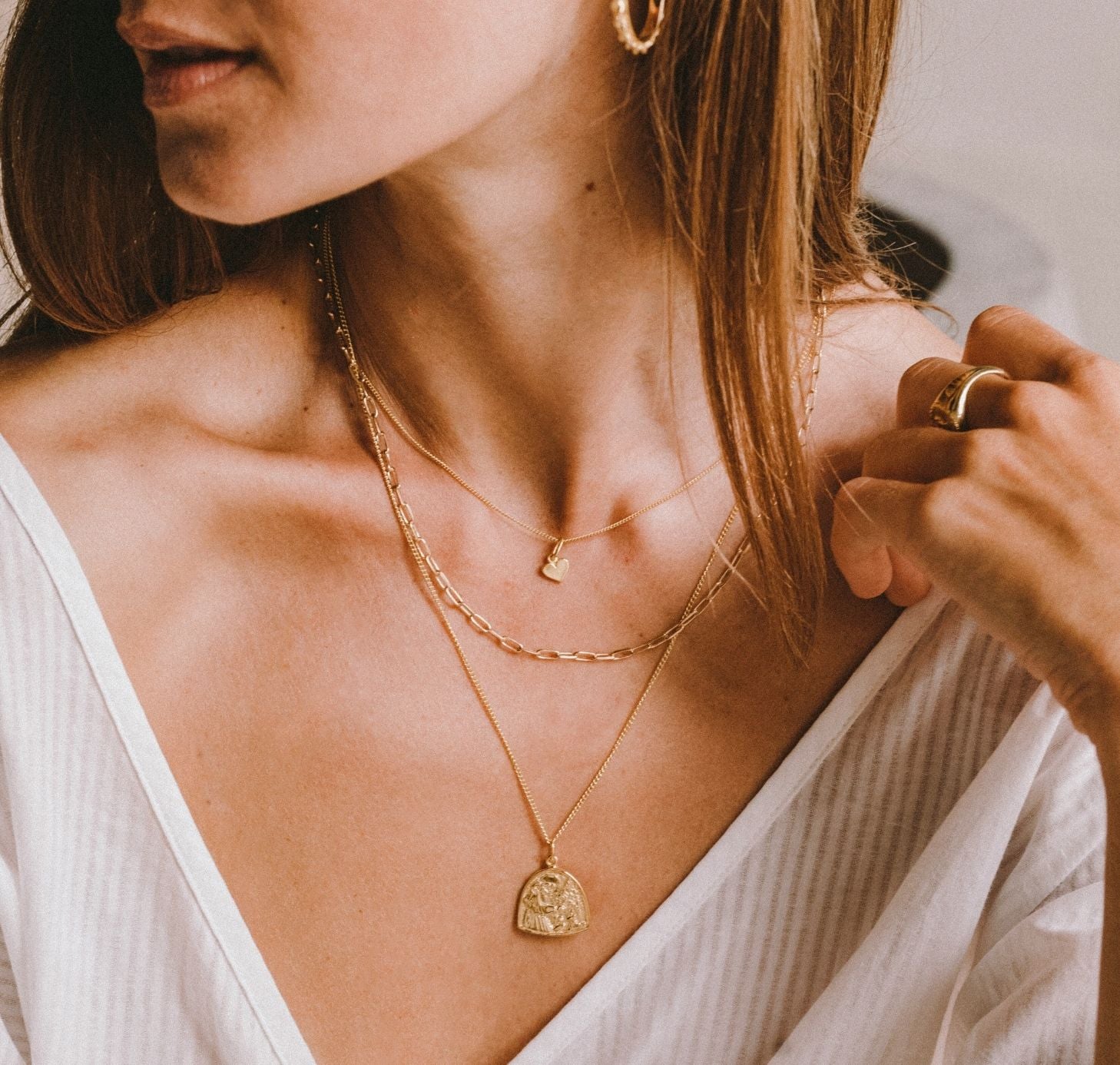 a woman wearing St Assisi pendant gold and other layers