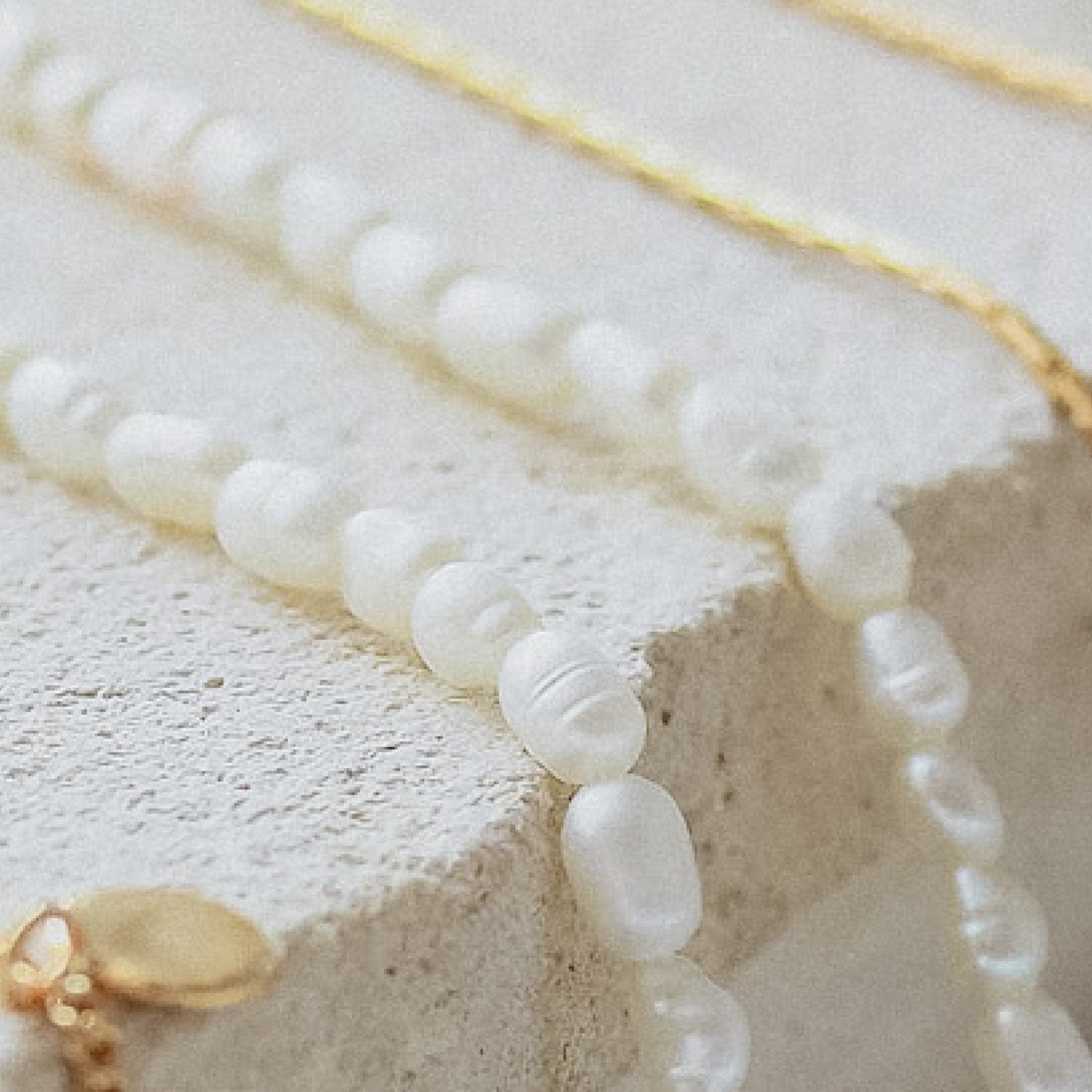 Timeless Mini Pearl Anklet - Gold displayed on beige stone