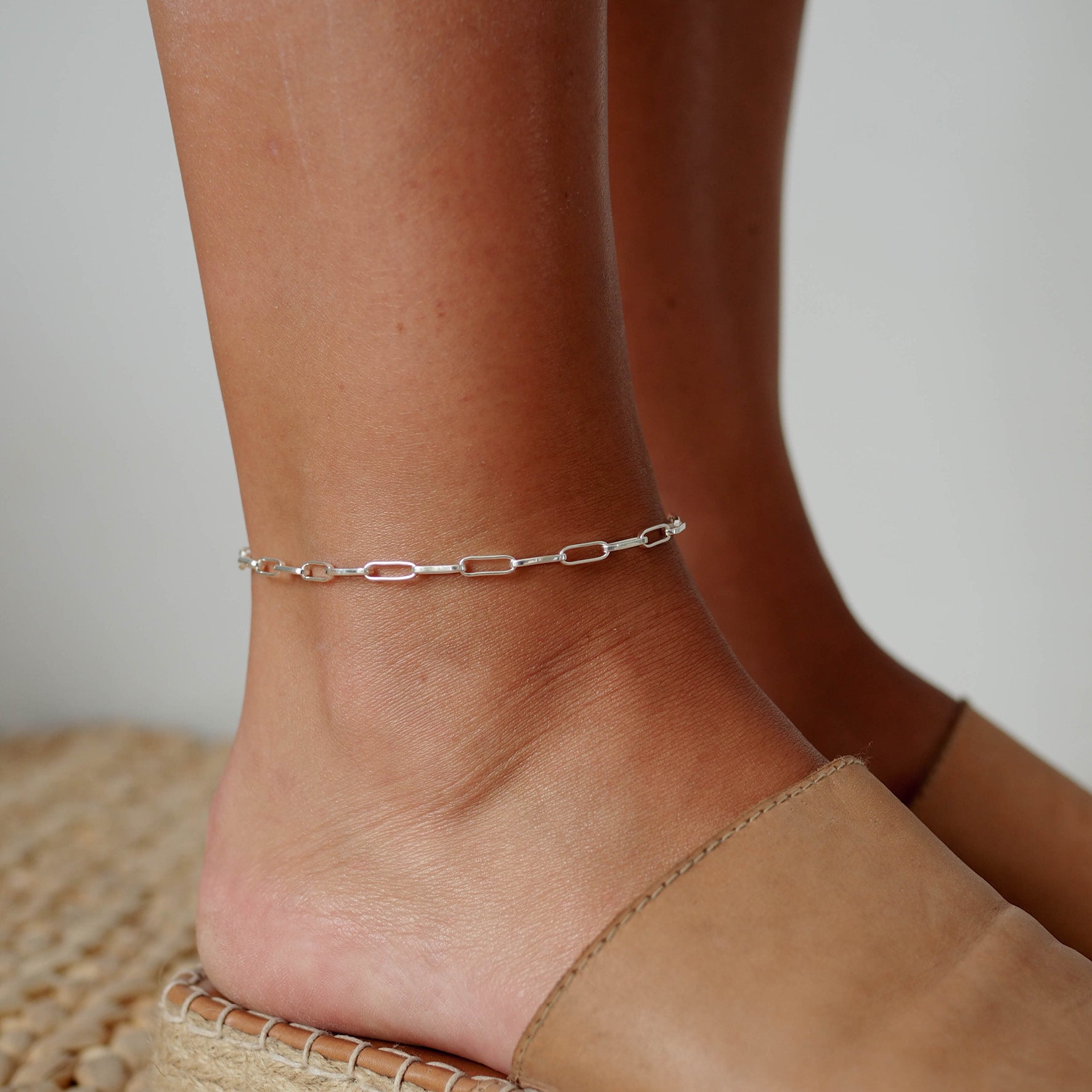 a woman wearing washington paperclip silver anklet on her