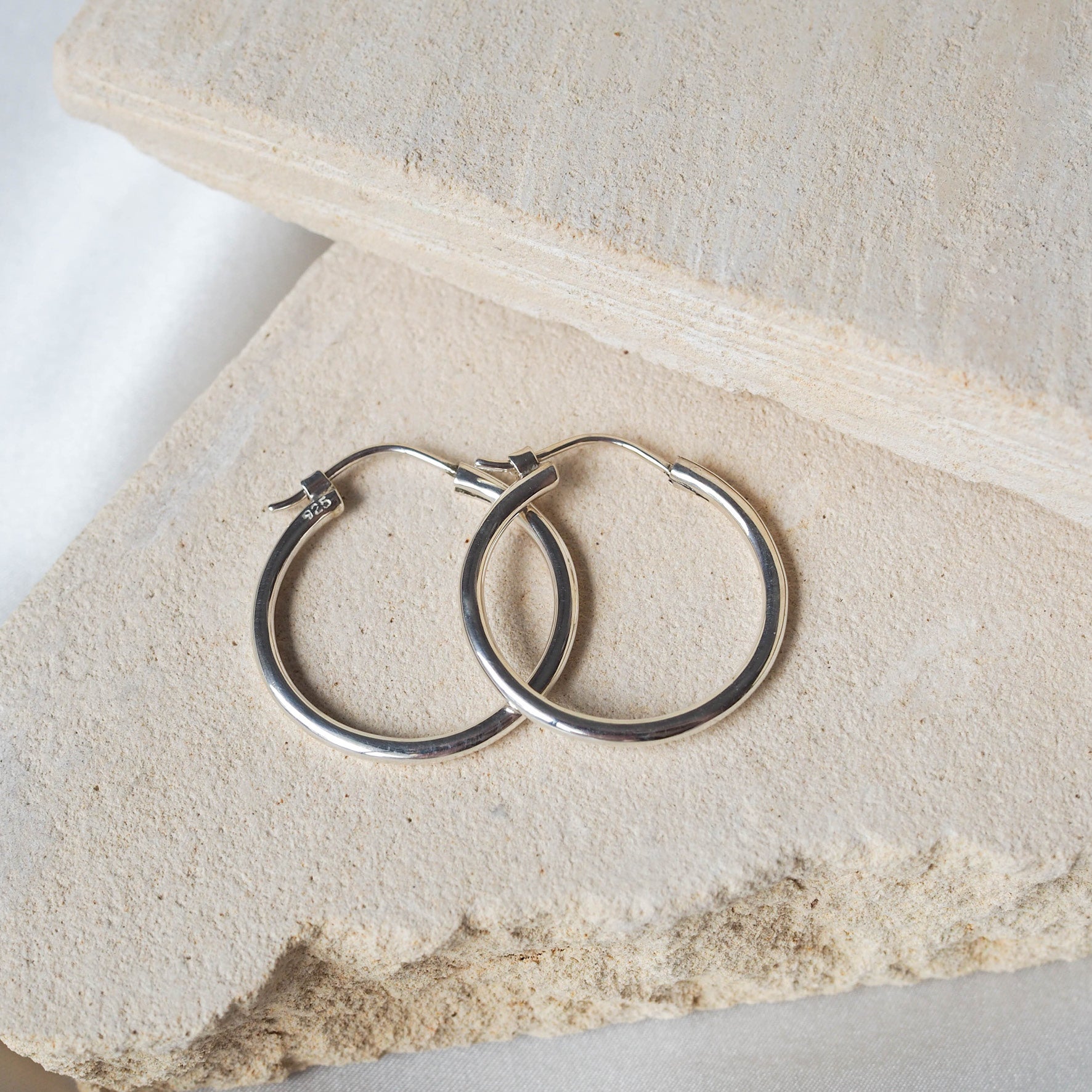 Signature Hoops 25mm Midi - Silver displayed on beige stone
